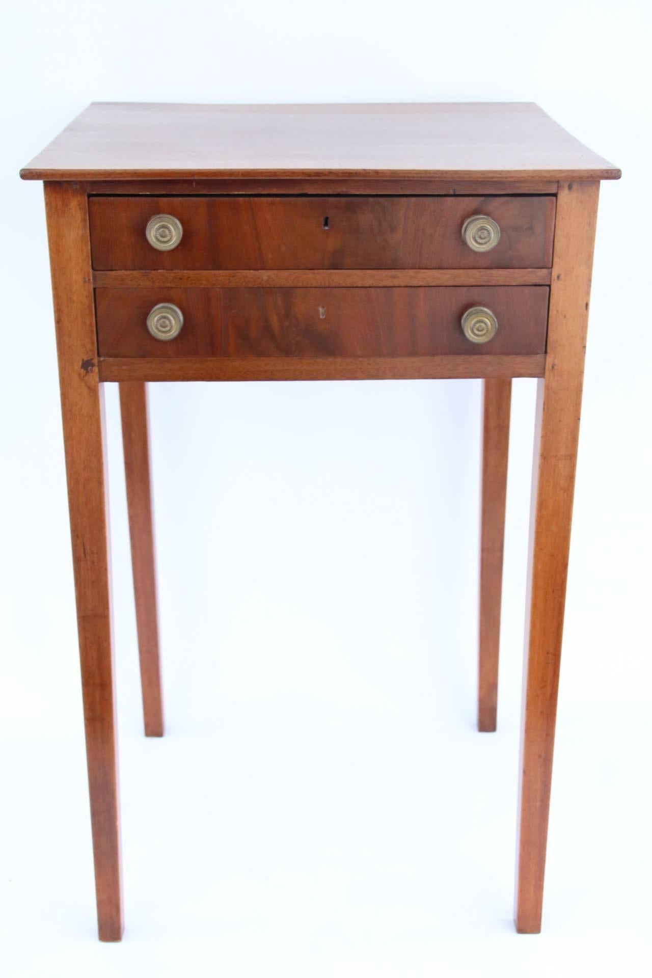 Hepplewhite mahogany two-drawer stand with delicate tapered legs and dovetail construction. Original brass pulls. Wonderful delicate size.

New England, circa 1810.

Measures: 29