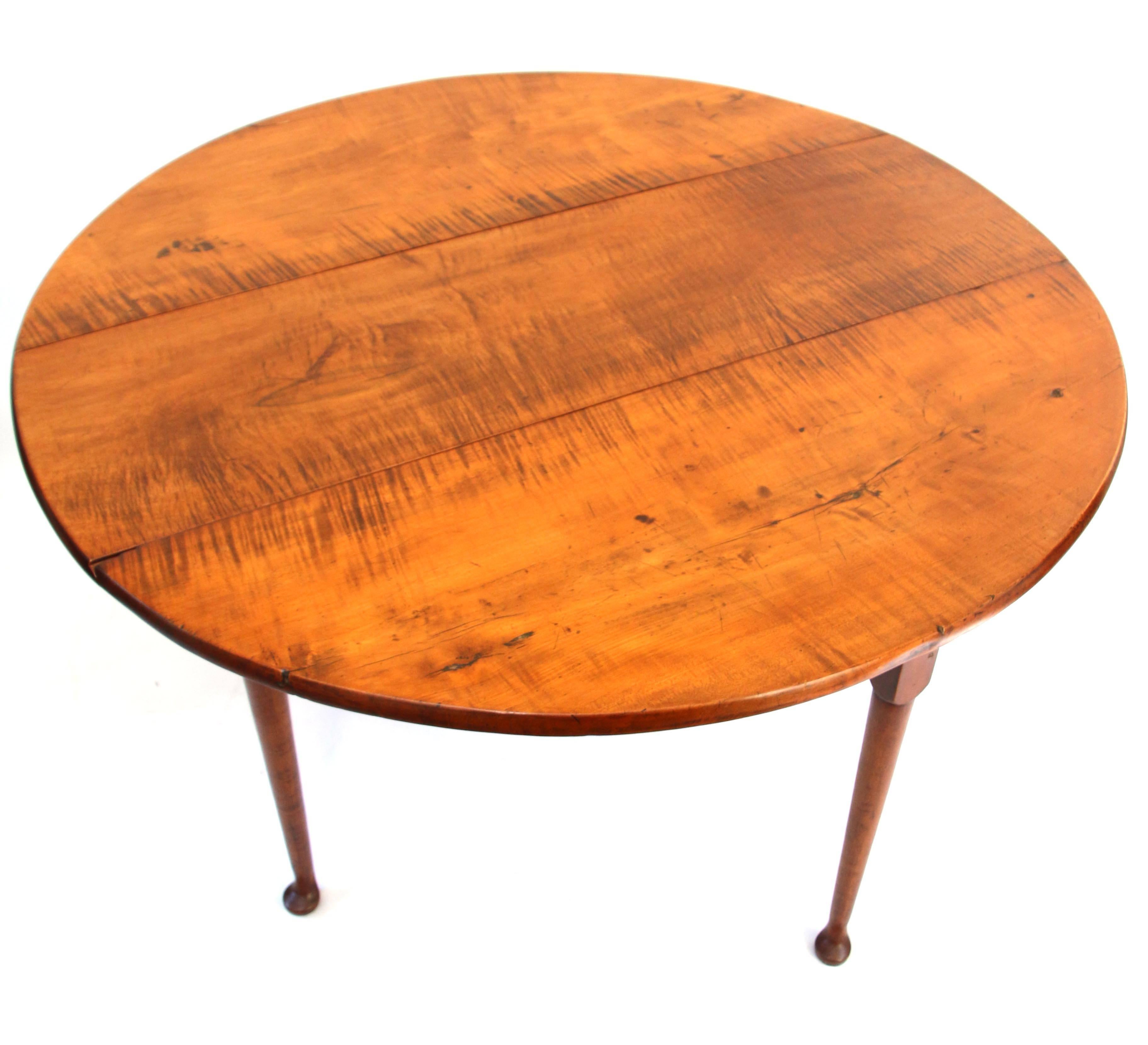 Queen Anne tiger maple drop-leaf table, the circular top above a straight skirt joining tapering legs ending in pad feet. Original hinges on leaves as well as original wooden hinges and dowels in swinging legs. Minor loss at edge of one leaf as