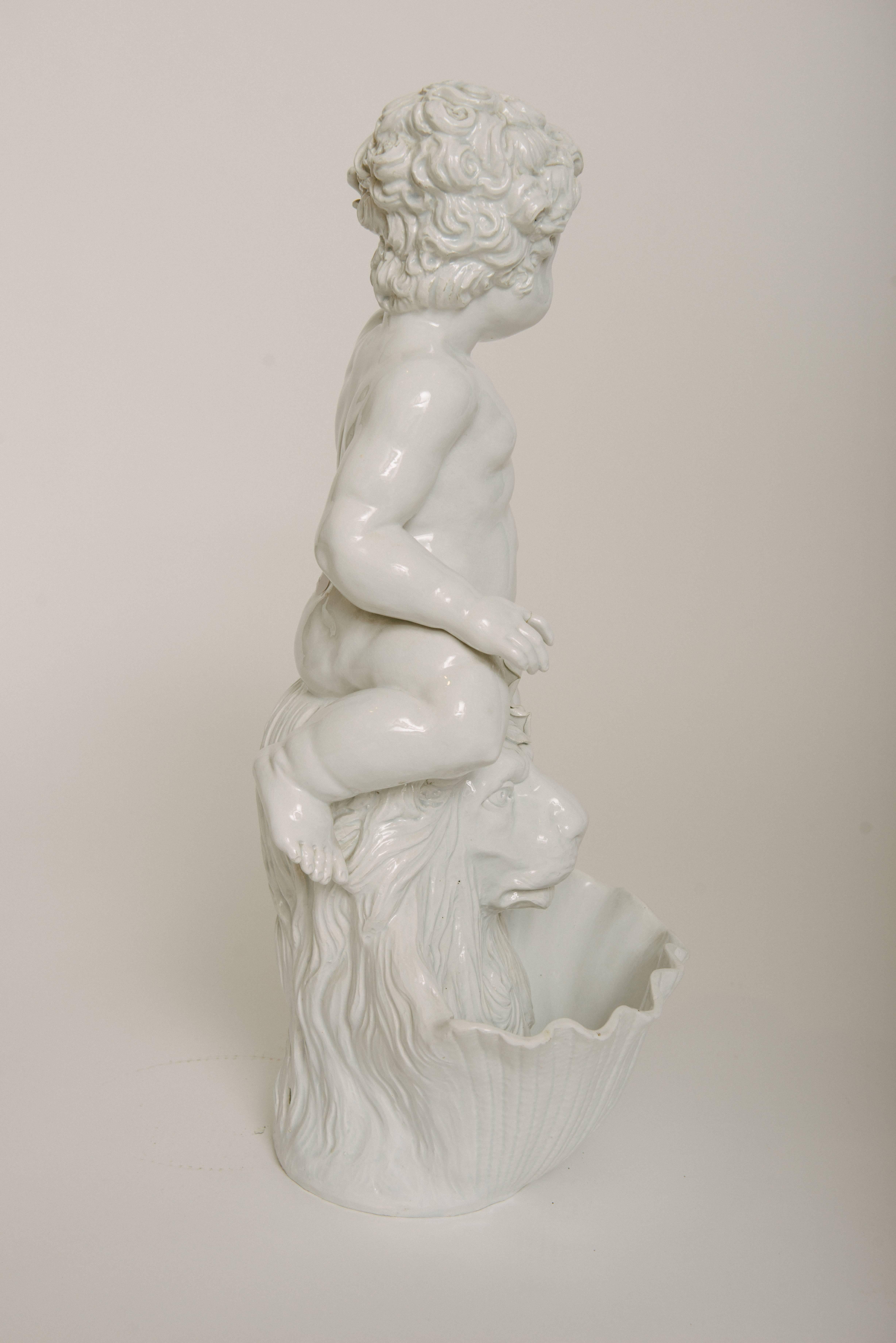A vintage Italian Blanc De Chine fountain of a beautiful putti sitting atop a lion's bust bowl. This piece is a wonderful decorative centerpiece on its own.