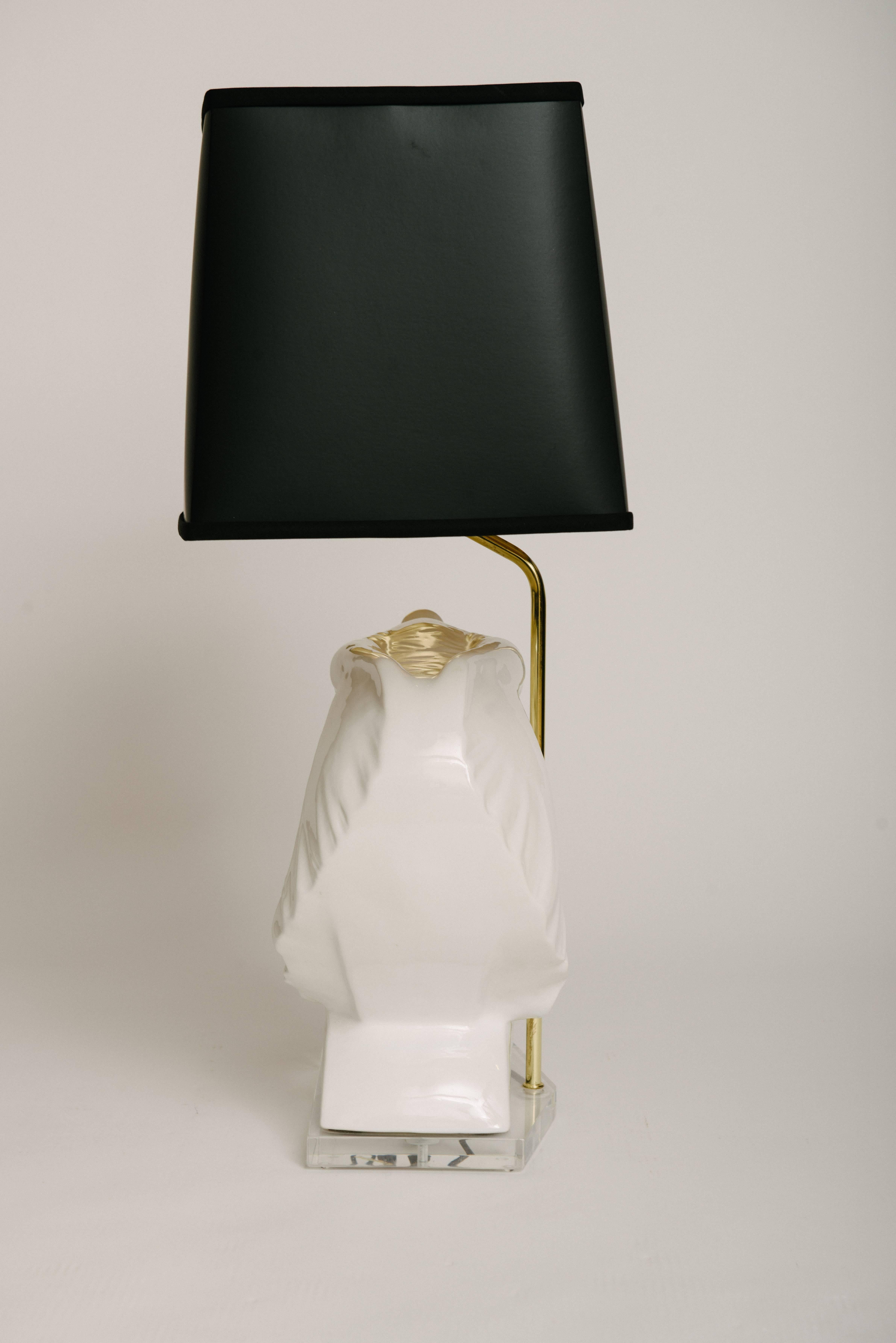 A Hollywood Regency white ceramic elephant bust table lamp on Lucite base with custom gold lined black paper shade. This lamp is newly wired.

Two are available, a left and right facing elephant bust.

Ceramic elephant bust dimensions only: 19W