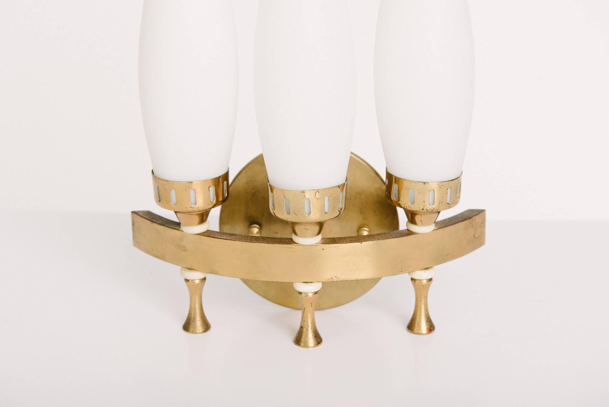 A pair of Italian brass and white glass Stilnovo style three-light sconces, newly wired.