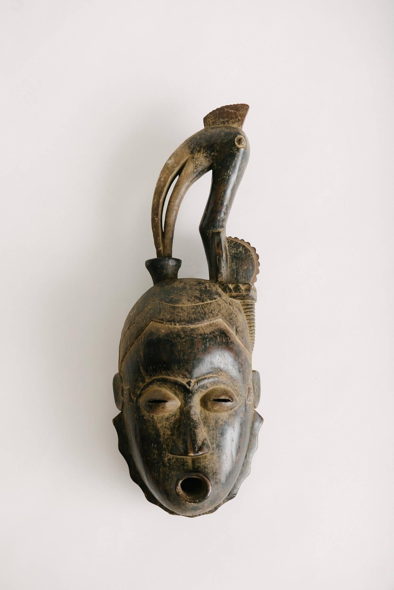 A vintage pair of left and right wood carved Gouro Guro tribe style African masks from the ivory coast. Nicely carved details on the face and bird on head.
 
