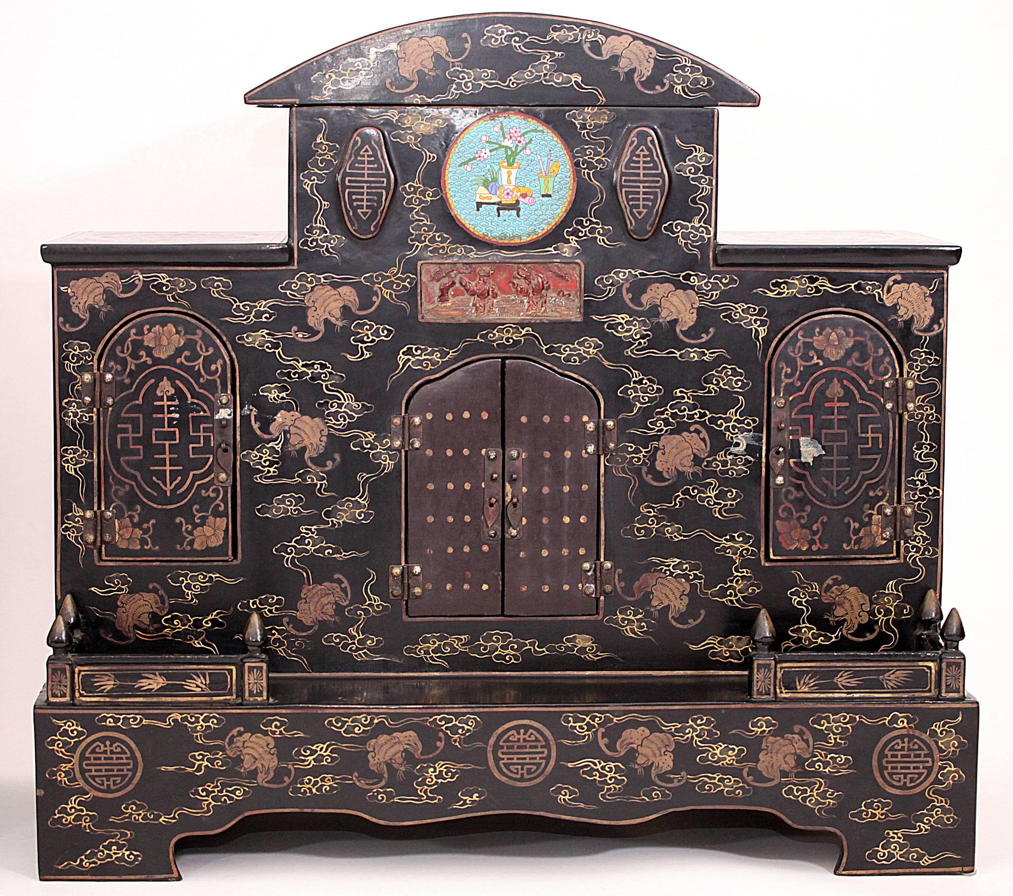 Pair of early 20th century Chinese hand painted black lacquered ancestral shrines. Each shrine features three sets of double doors, a carved antique gilt panel and a cloisonné center medallion. Measures: 31.5 x 29.