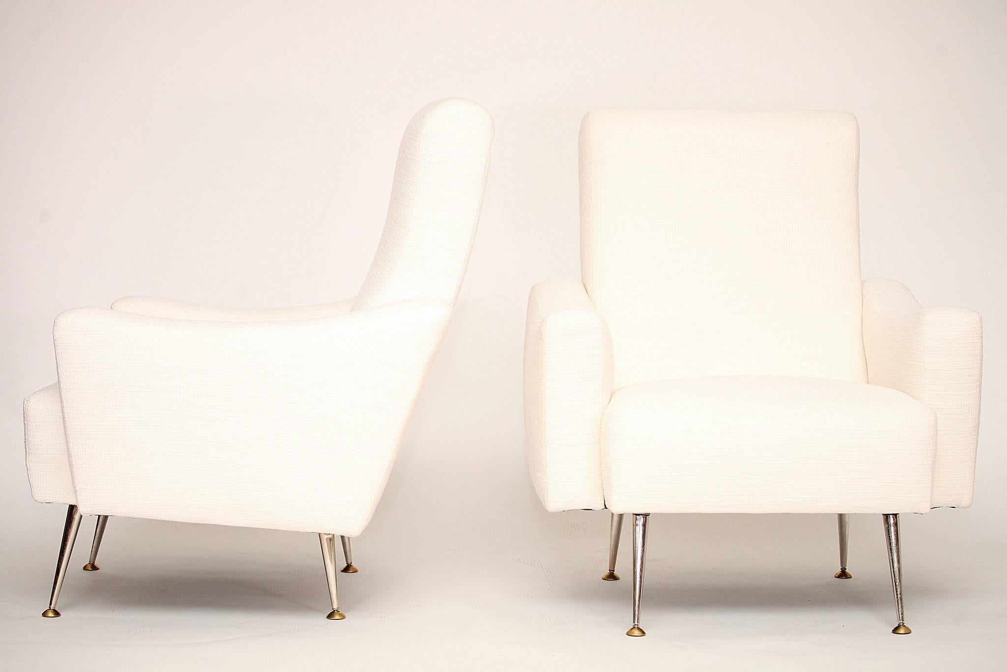 A sculptural pair of 1950s Italian armchairs newly upholstered in a tweed woven white linen blend with brass legs.