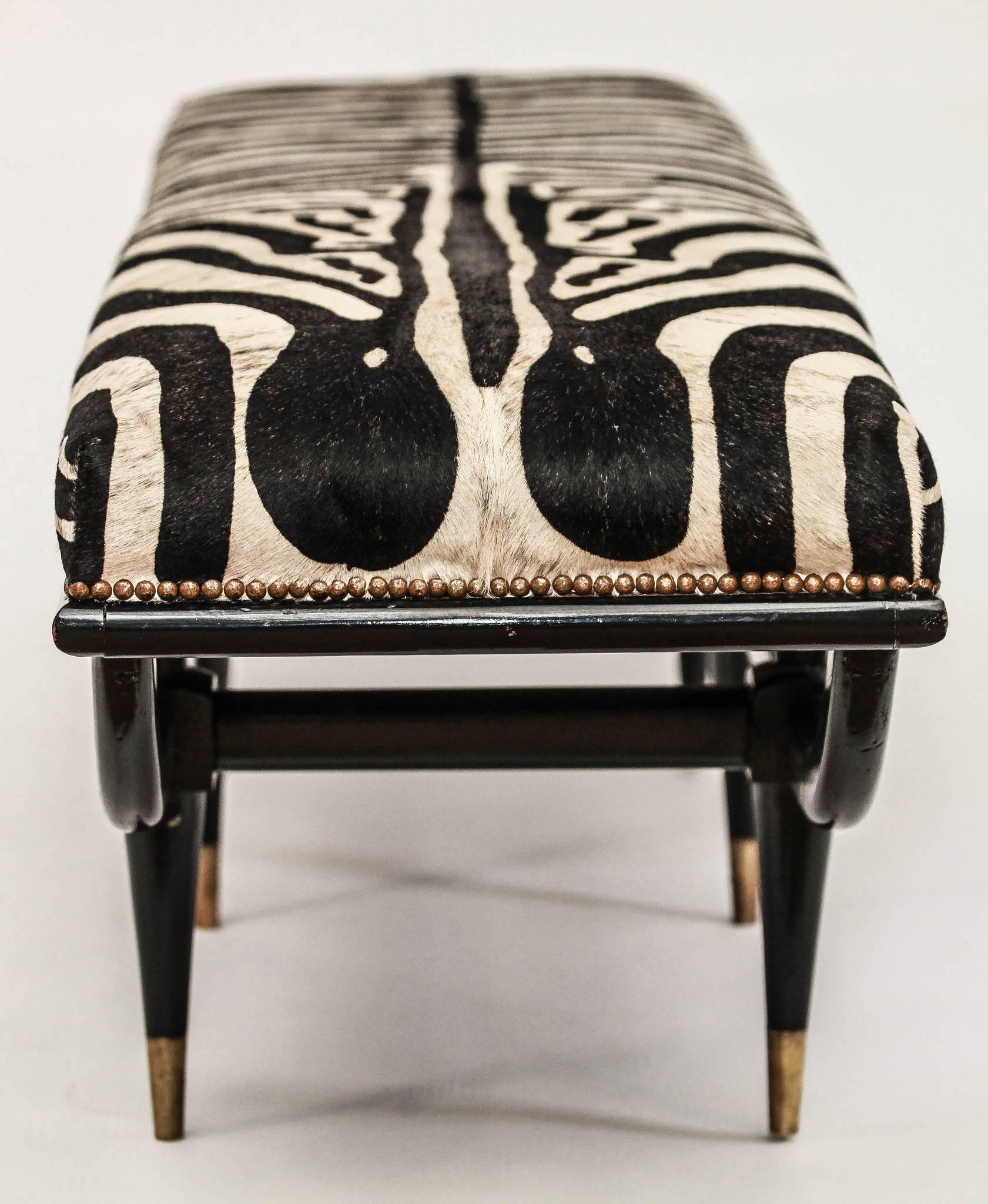A Mid-Century Italian ebonized bench upholstered in a handsome zebra printed hair hide with bronze sabots.