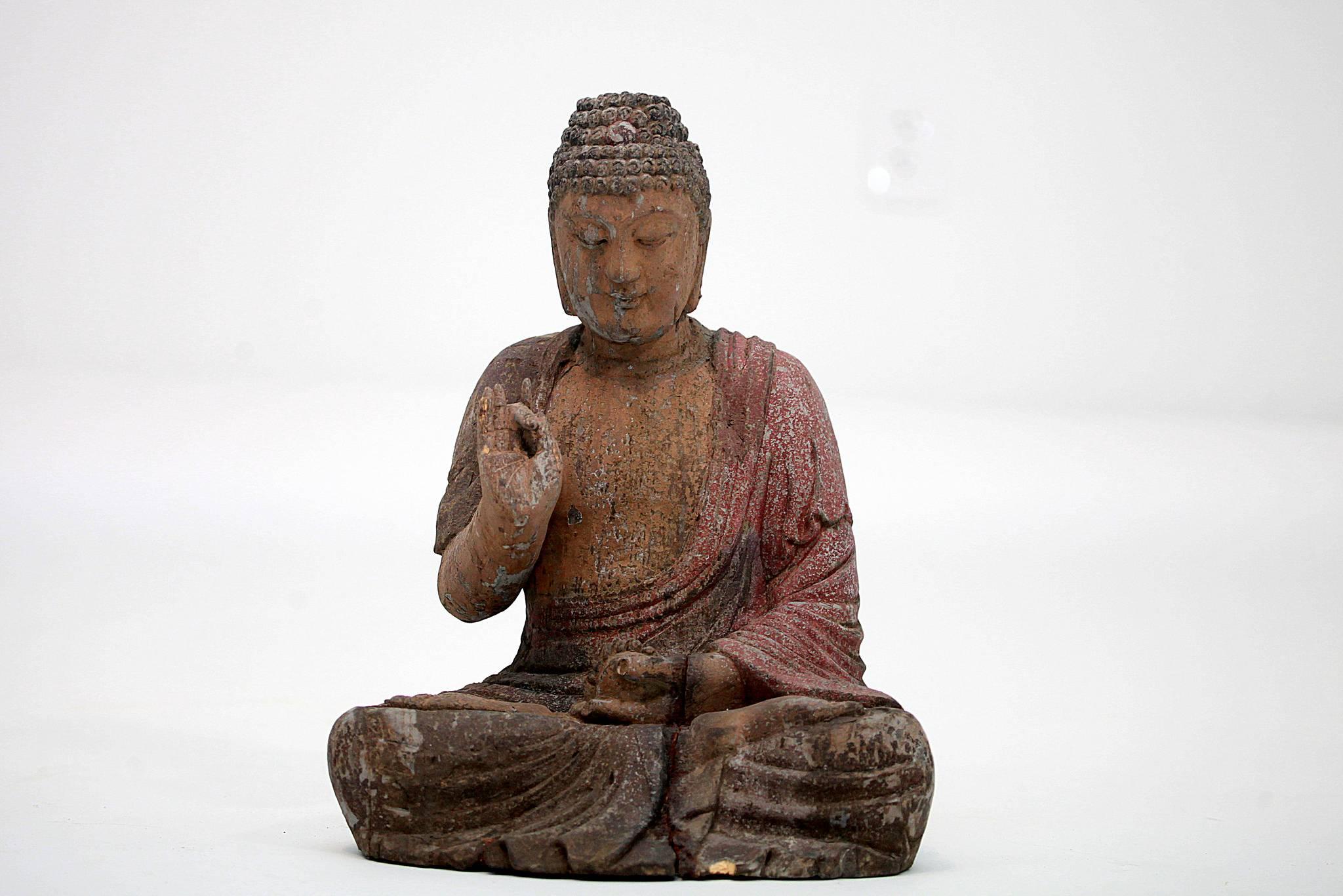 An seated carved polychrome seated Buddha.

This imposing wooden sculpture depicts the Dharmachakra Mudra seated in padmasanam (lotus position) and the hands in an On Ta position symbolizing wisdom and patience.. The Buddha is bare-chested and wears