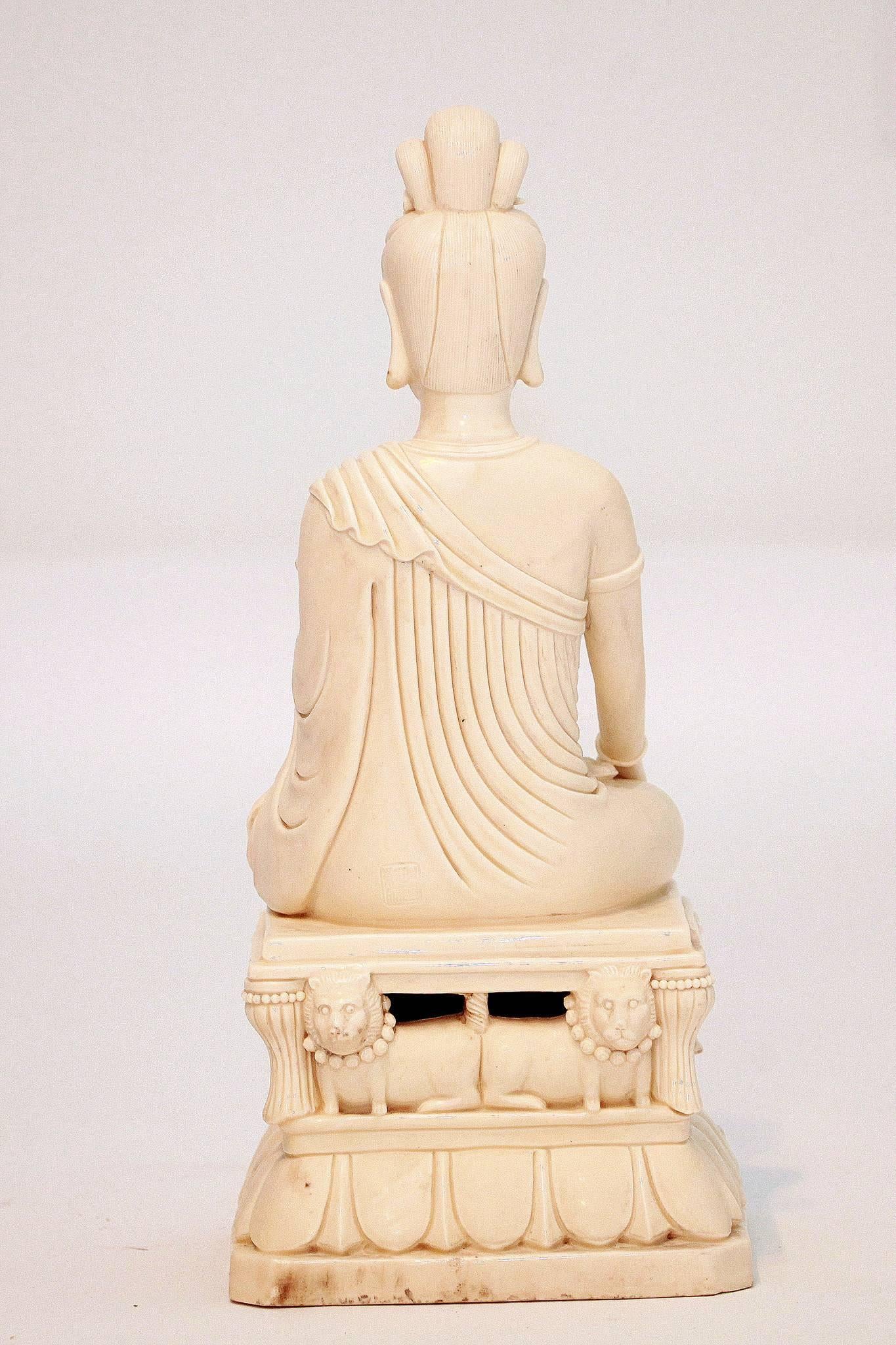 An early 20th century signed Chinese Blanc de Chine Guanyin (Quan Yin) styled in a ruched robe, Buddha crown, holding a cloud septor and seated on a pedestal with four lion dogs.