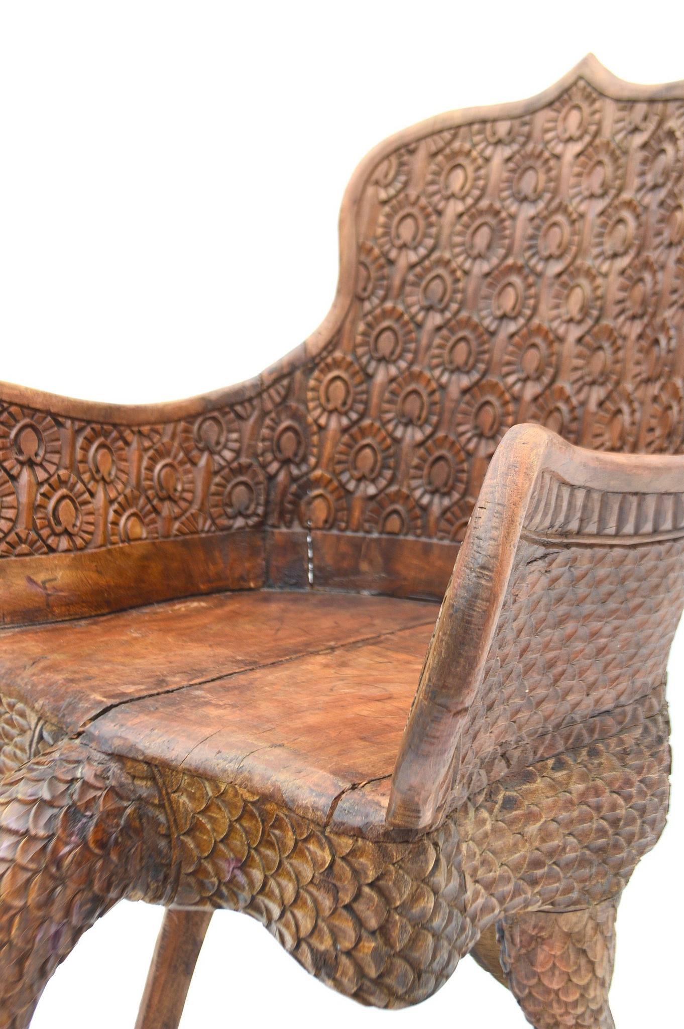 A wonderfully carved Anglo-Indian peacock chair featuring head and tail as legs. This vintage chair is heavy, sturdy and structurally sound.