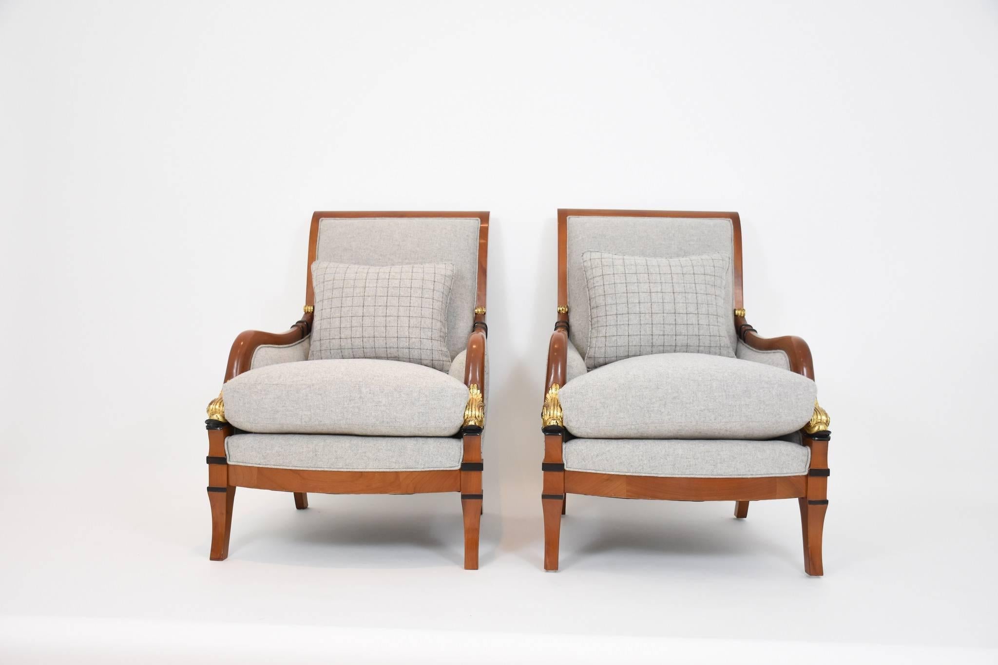 A pair of vintage fruitwood Biedermeier style carved dolphin bergéres with black patinated and gold gilt detailing. Chairs are newly rebuilt upholstered in a grey and grey checked wool blend with coordinating lumbar pillow.