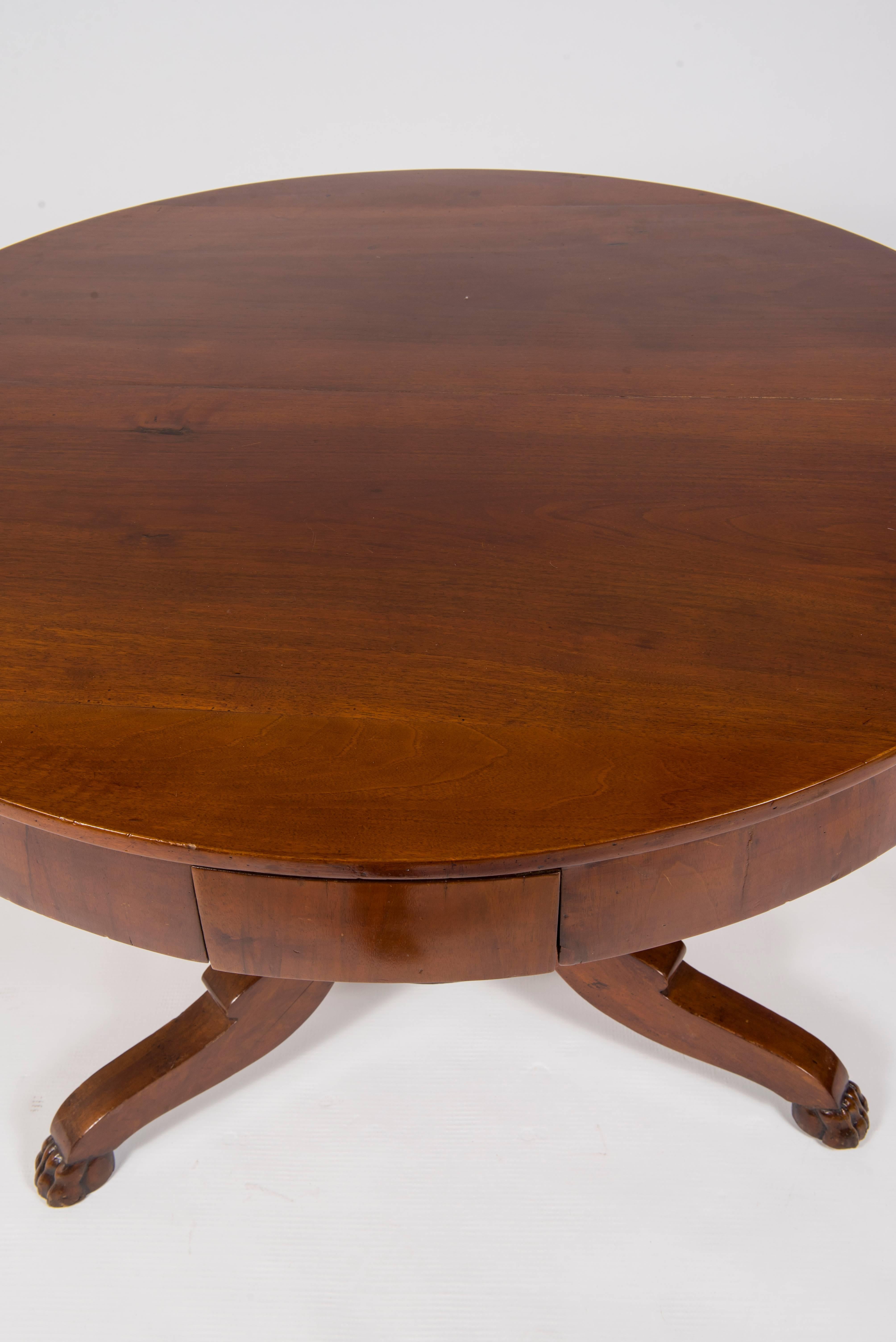 An Italian Empire walnut centre table featuring two drawers, three legged pedestal base and classically carved lion's paws, circa 1815.