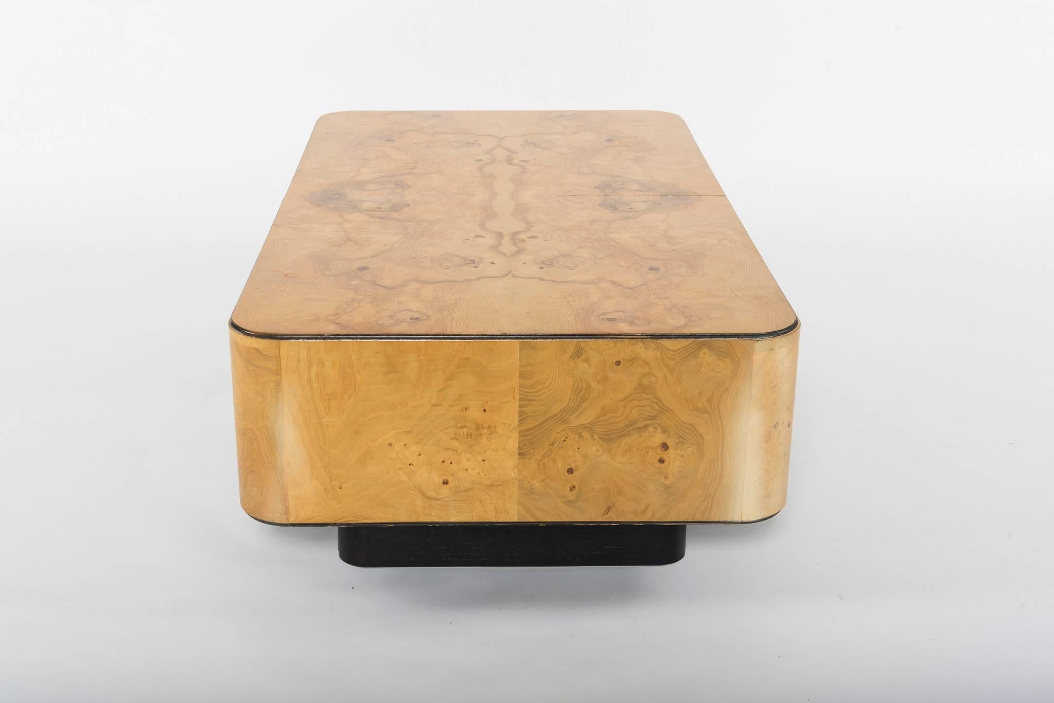 A handsome John Widdicomb burl wood cocktail table with black base. This great piece has a beautiful match booked top with hidden storage area that can even house a bar.