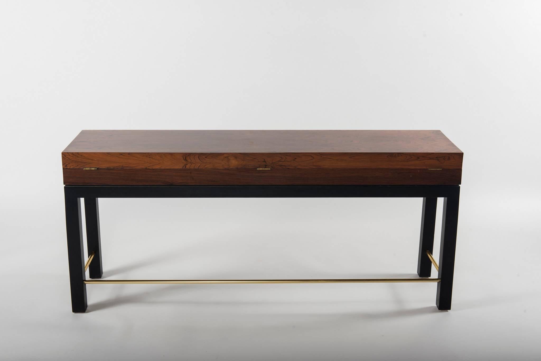 A hardwood long chest with ebonized legs and brass stretcher.