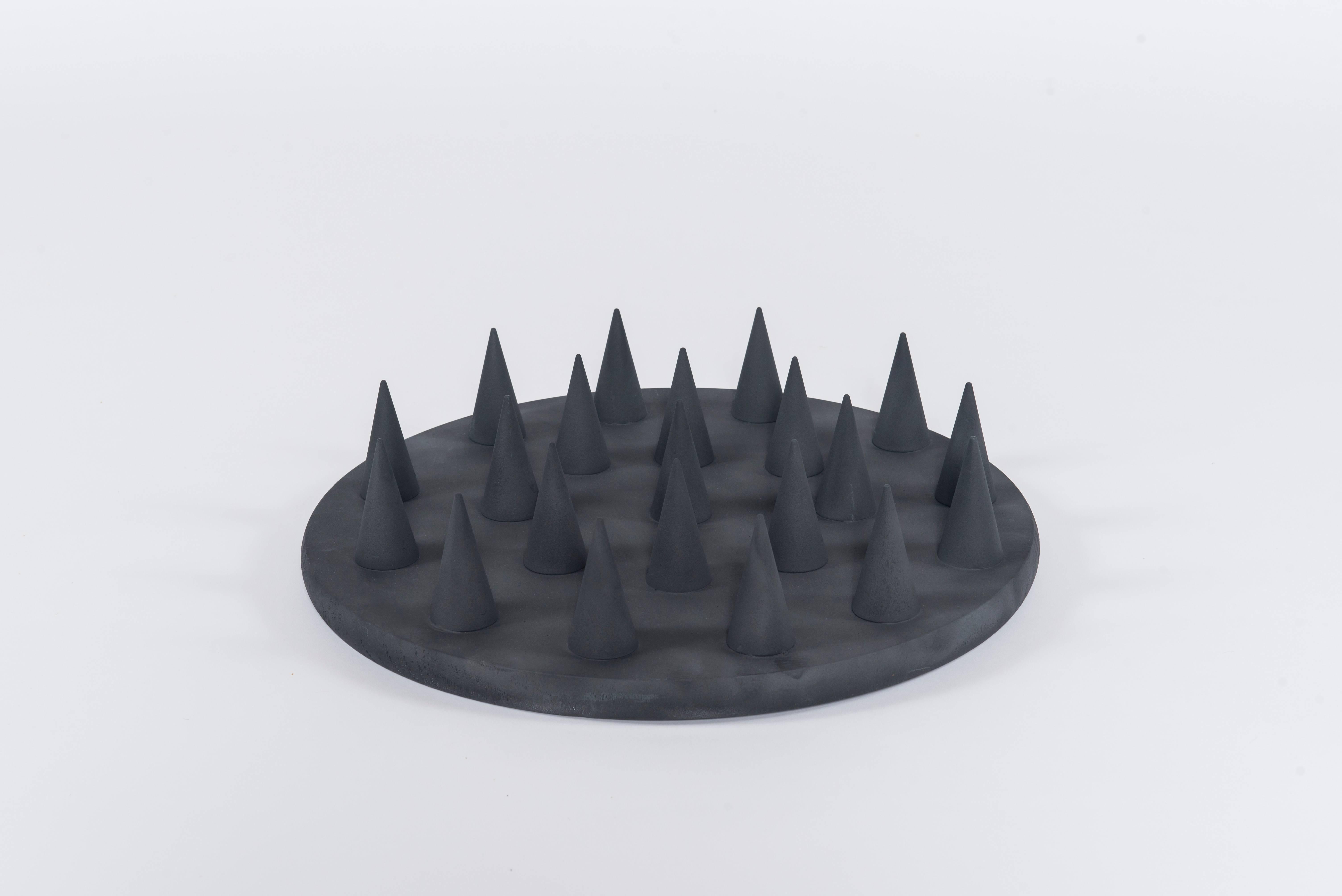 A geometric wall sculpture of black wooden spikes.