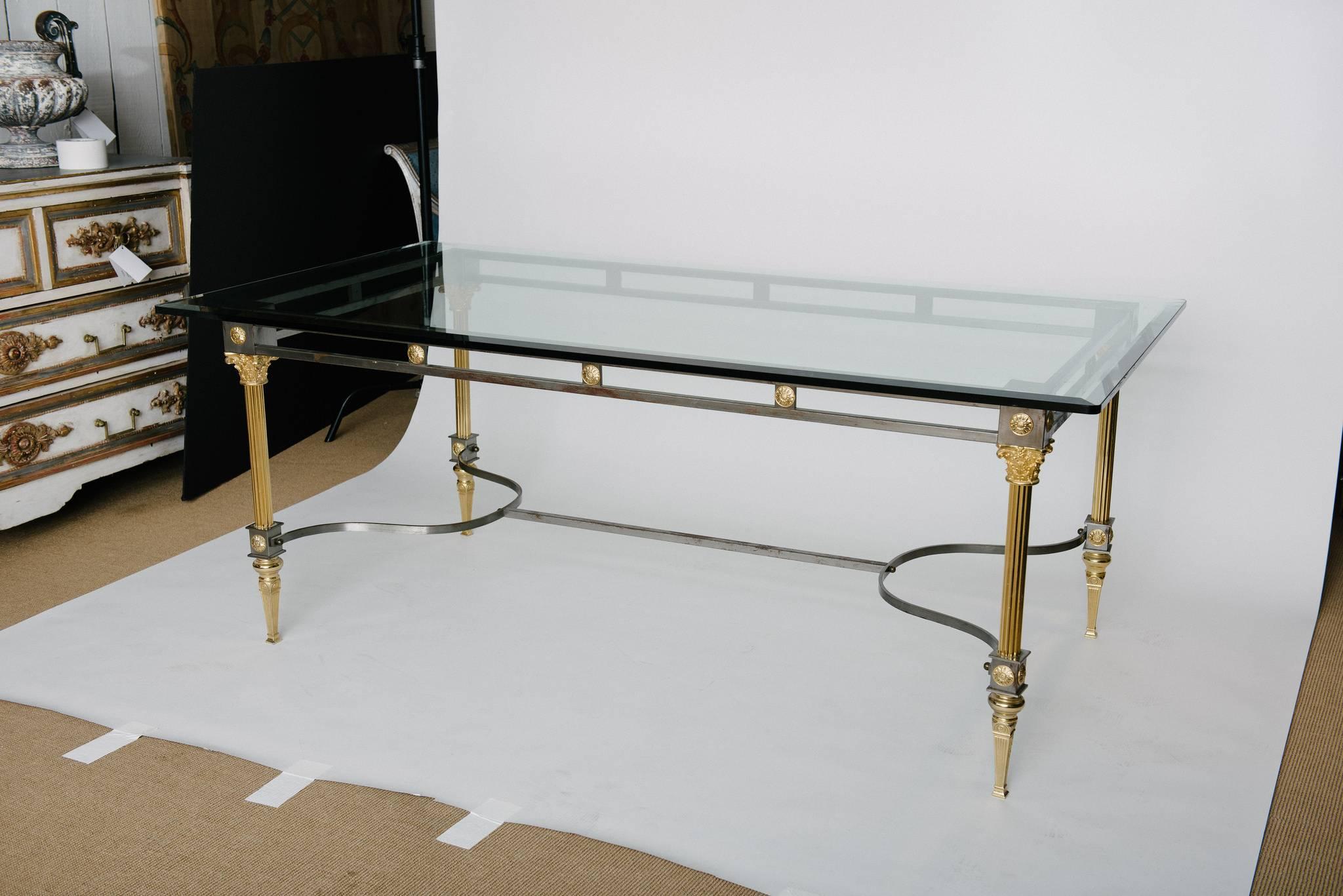 Steel and brass dining table by Maison Jansen. Features Corinthian style capitols with fluted columns on each corner supporting the top with gilt French rosettes. The table has a lovely patina on the steel and brass that could be polished or enjoyed