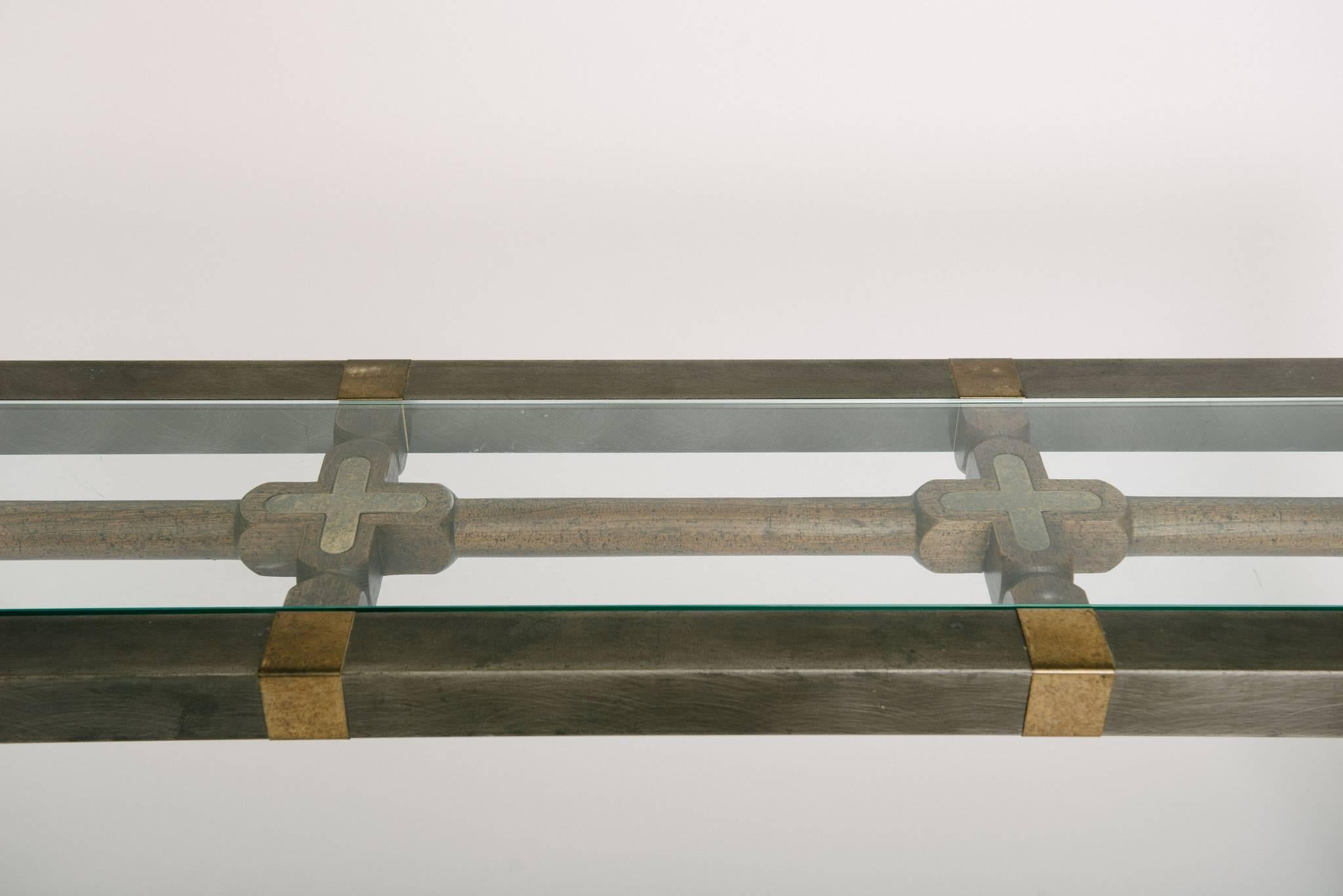 A mixed-media midcentury console or sofa table of brushed steel, brass, a geometric carved wooden centre inlaid with brass, and glass top.