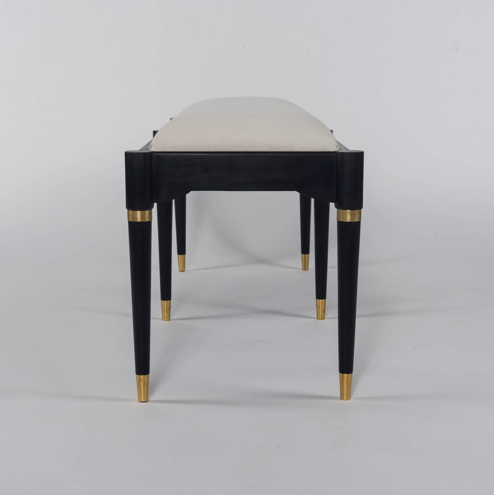A custom ebonized and brass Tommi Parzinger style bench with a white ecru linen seat. 

Also available C.O.M. We will professionally upholster this item quickly in your fabric supplied at no charge.