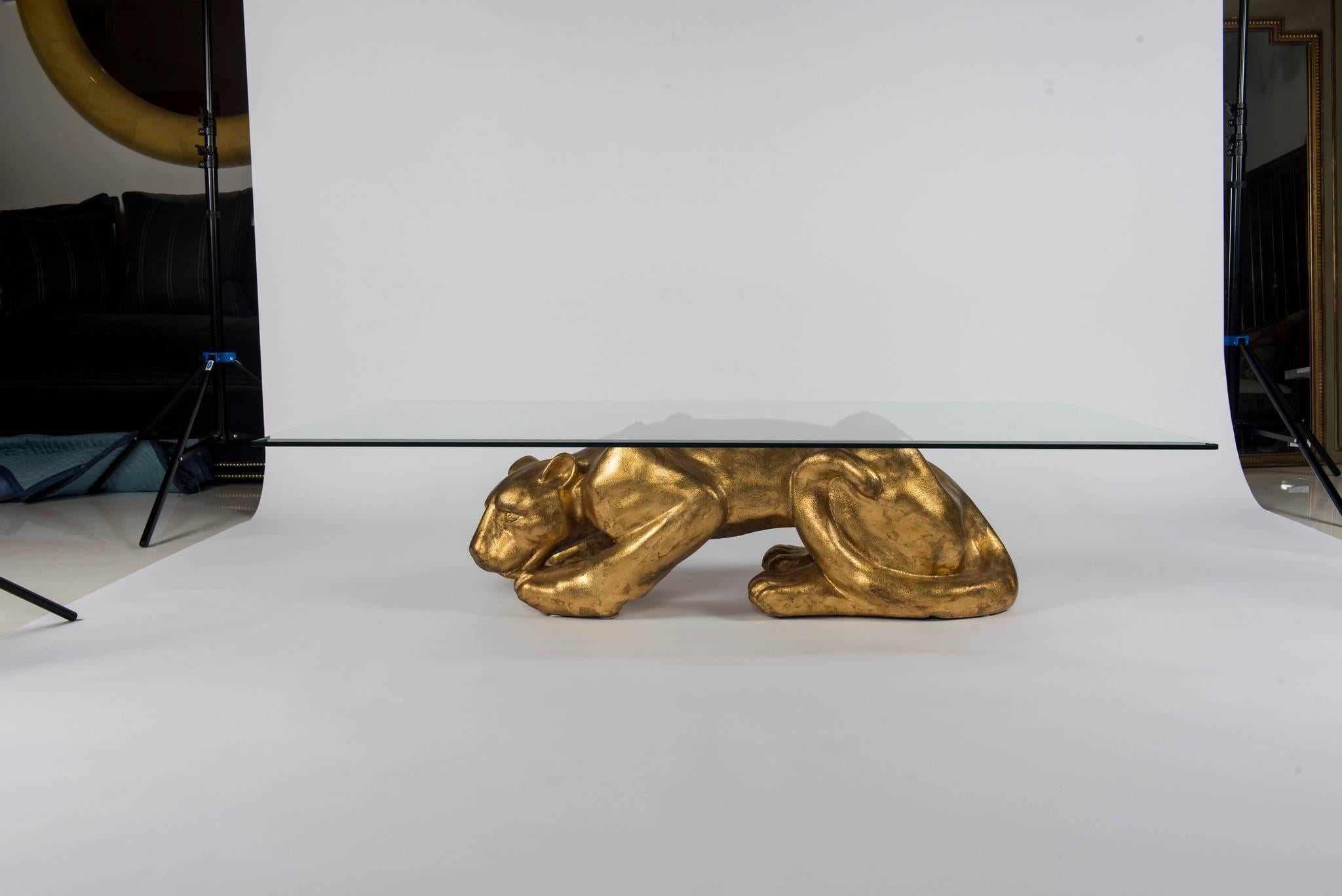 A chic 1970s gilt panther cocktail table with beveled glass top.