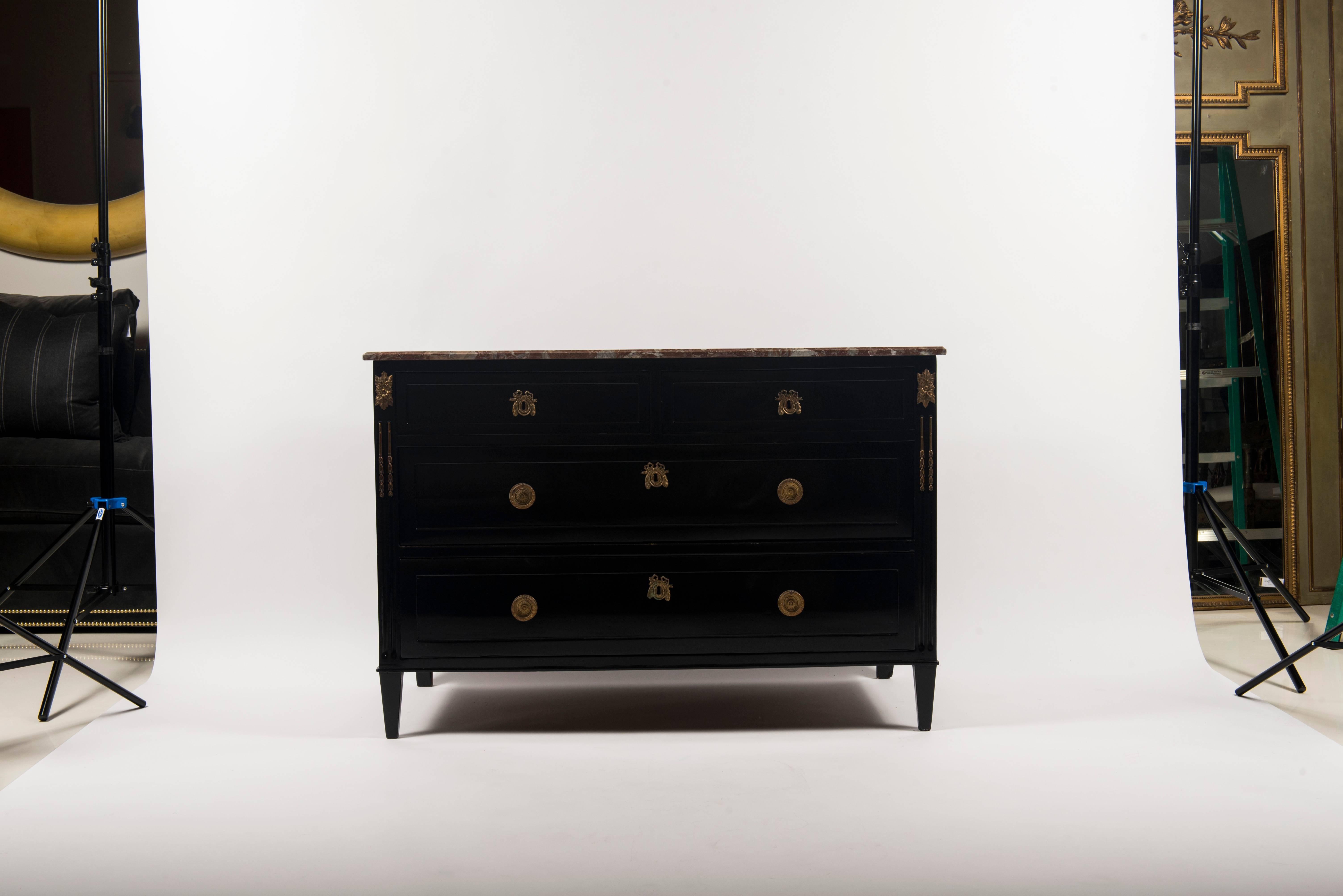 A 1940s French black lacquered Louis XVI style chest of drawers with rouge marble top with bronze ormolu and handles.