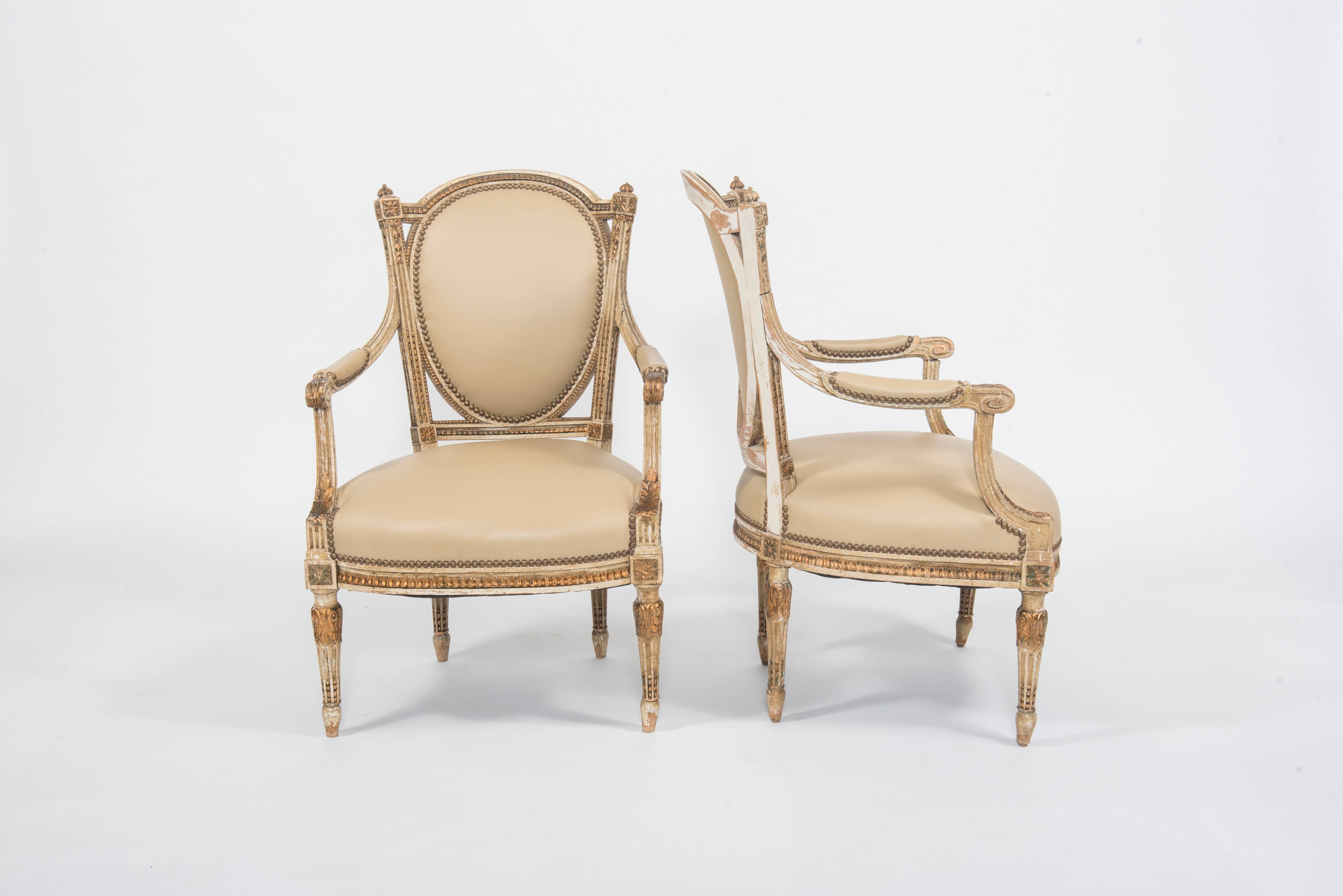 Pair of early 20th century painted and gilt French Louis XVI style fauteuils newly upholstered in an Italian blond bone colored leather.