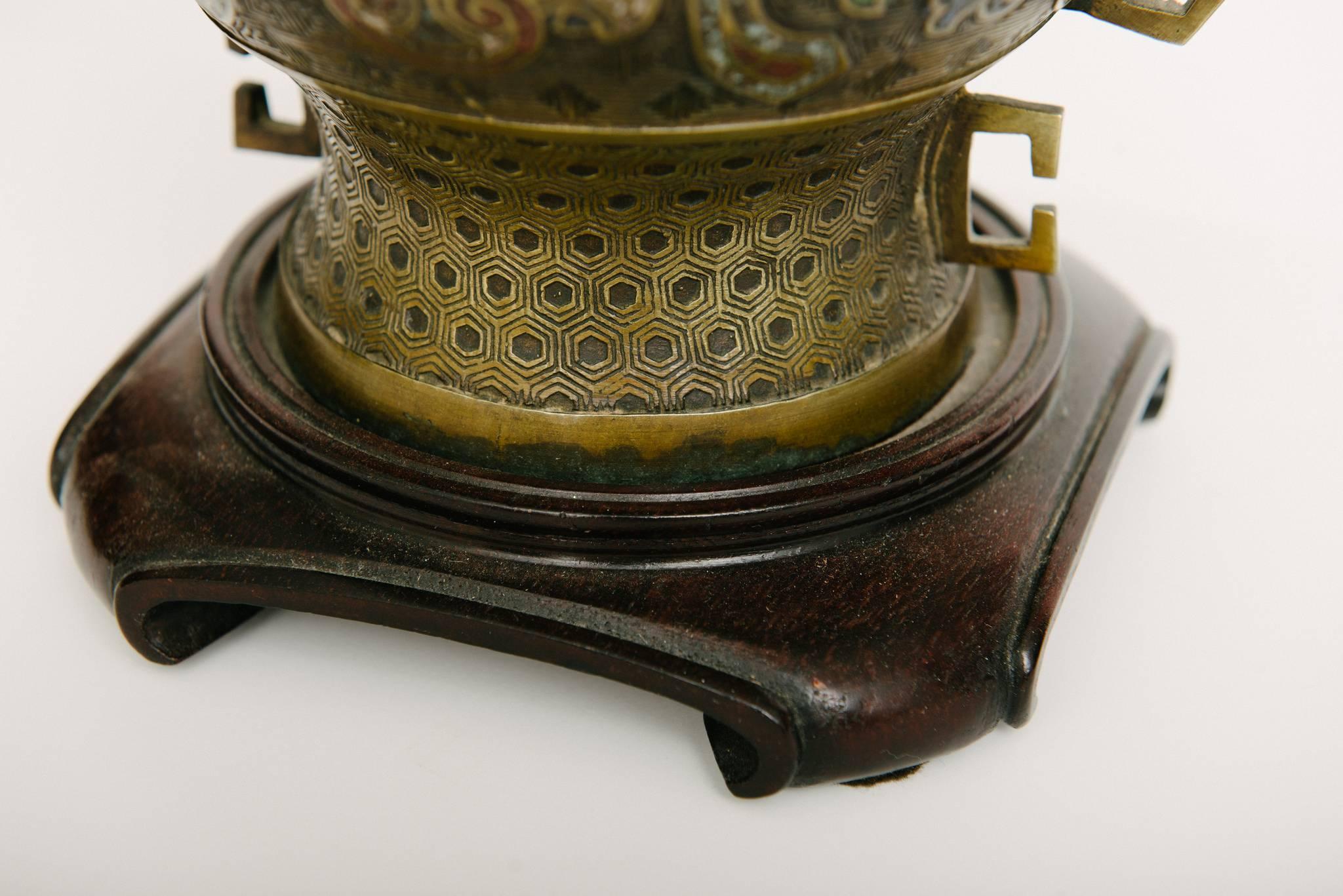 Antica lampada cinese in ottone e smalto con corniole e pietre turchesi su una base in legno intagliato. Mostrato con un paralume a tamburo modificato di lino bianco sporco del diametro di 12