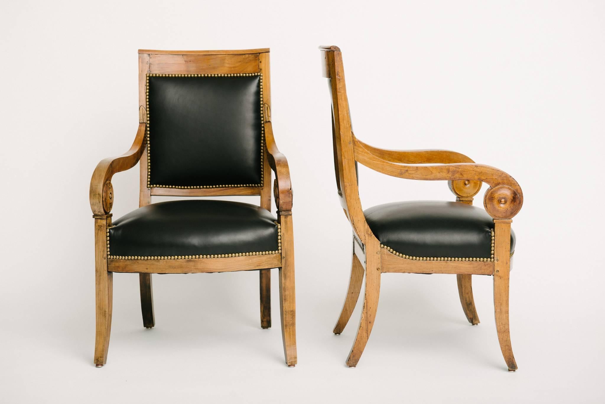 A handsome pair of Charles X armchairs newly upholstered in black lambskin leather with nailhead detail.