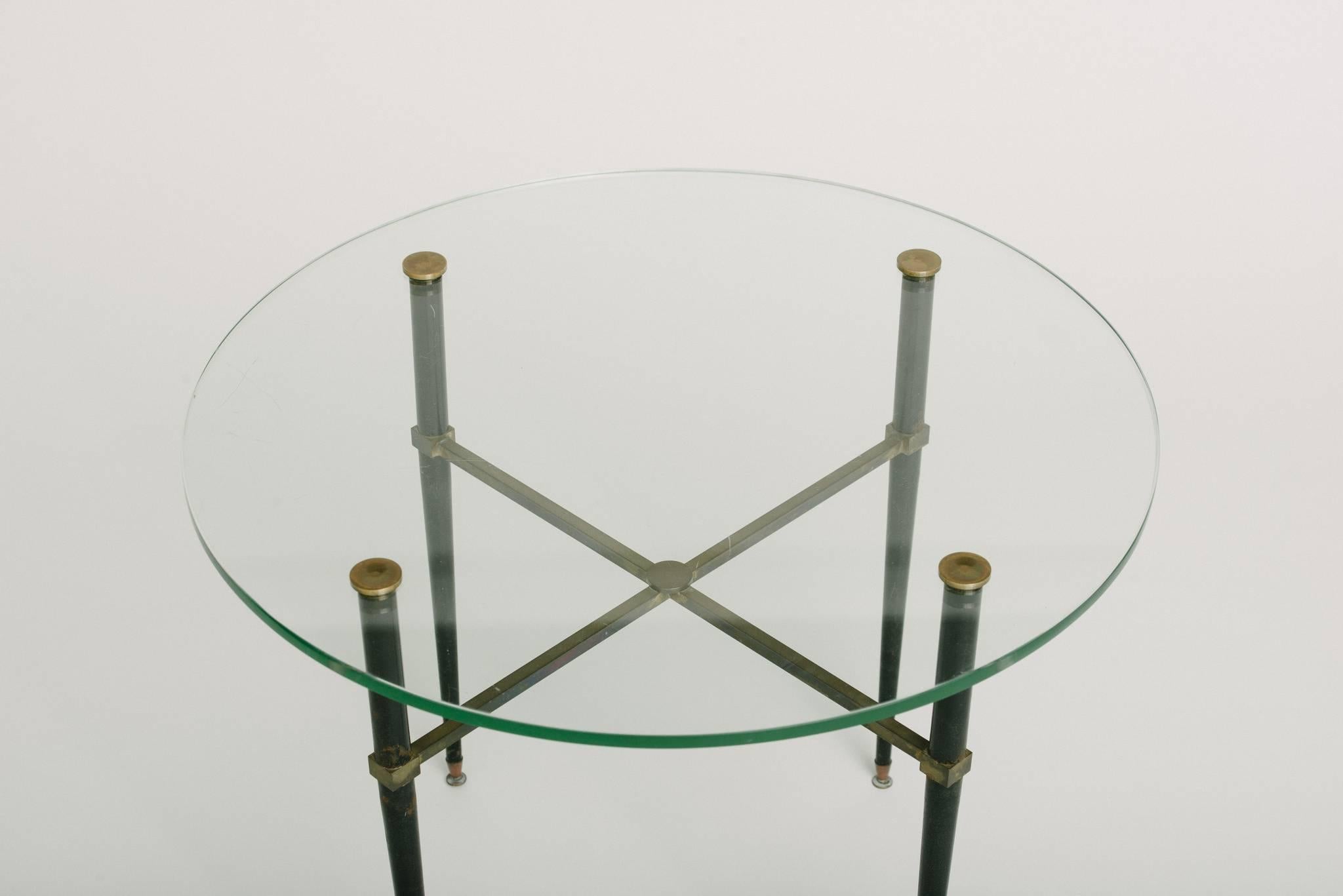 A 1940s stylized Italian round bronze table, patinated black legs, and glass top.