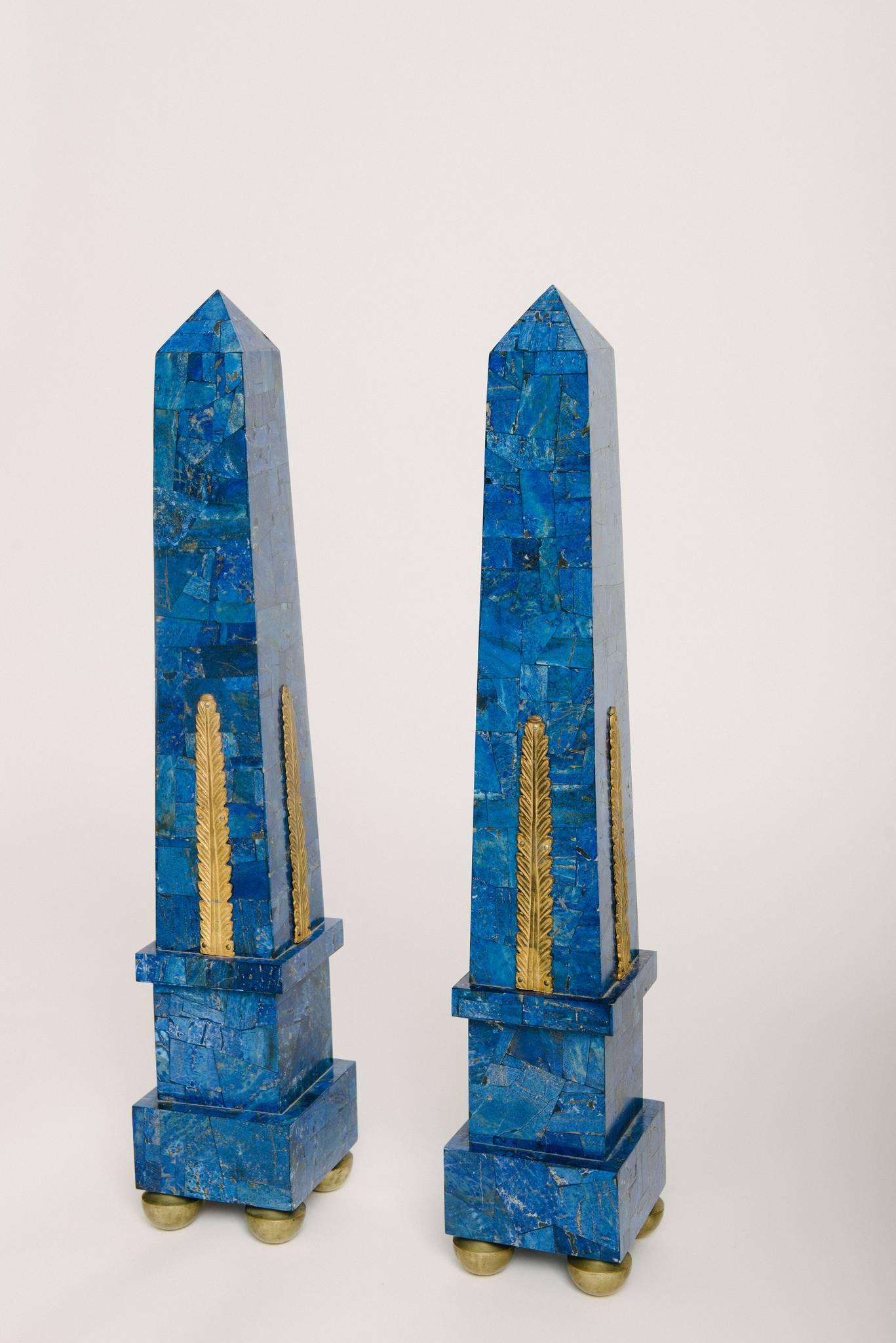 A stately pair of Continental neoclassical style lapis lazuli veneer obelisks with gilt cast bronze ormolu and feet.