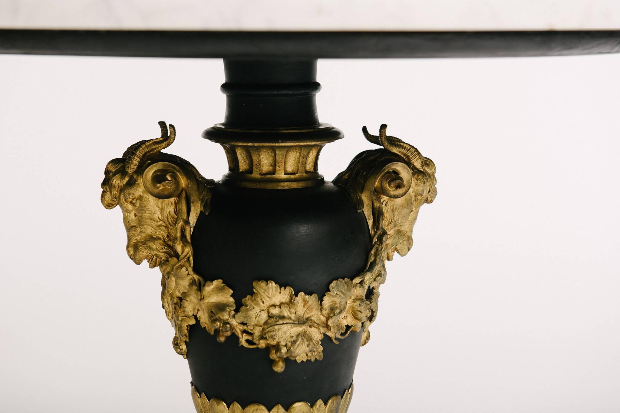 Französischer Gueridon im neoklassizistischen Stil des 19. Jahrhunderts aus patinierter Bronze mit weißer Marmorplatte. Dieser wunderschöne Tisch zeichnet sich durch Widderköpfe, Girlanden aus Eichenlaub und klassische Details aus.