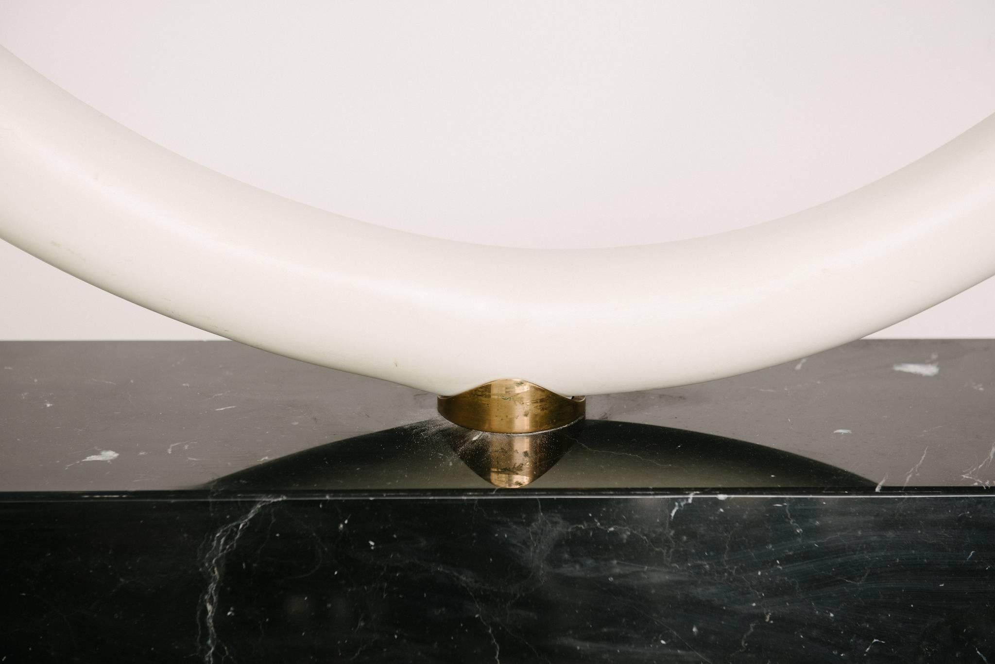 Faux elephant tusk console table mounted on a black marble base with glass top, circa 1970.
