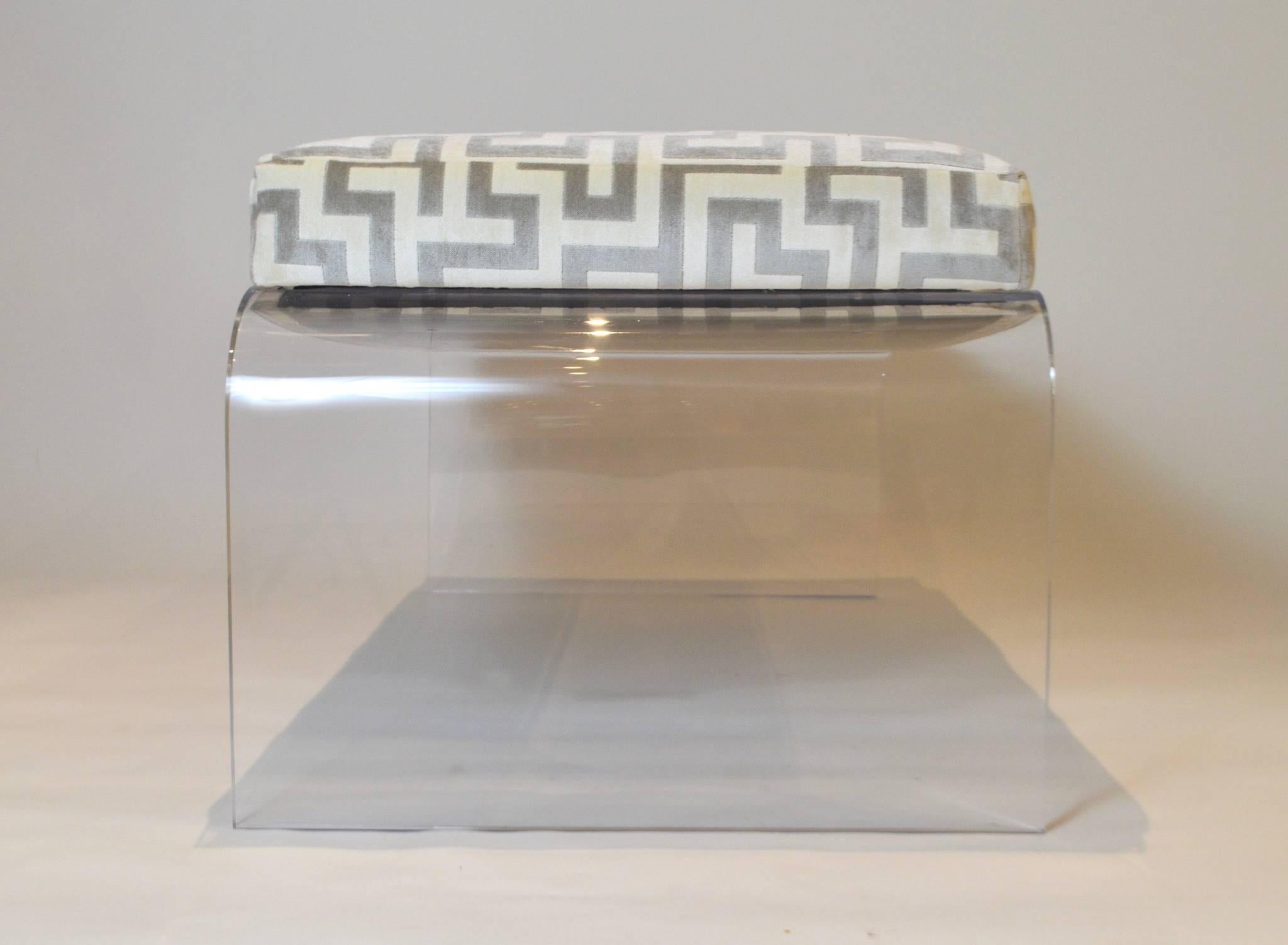 A vintage Karl Springer style Lucite bench, newly upholstered in a gray and white Greek key cut velvet, circa 1970s.