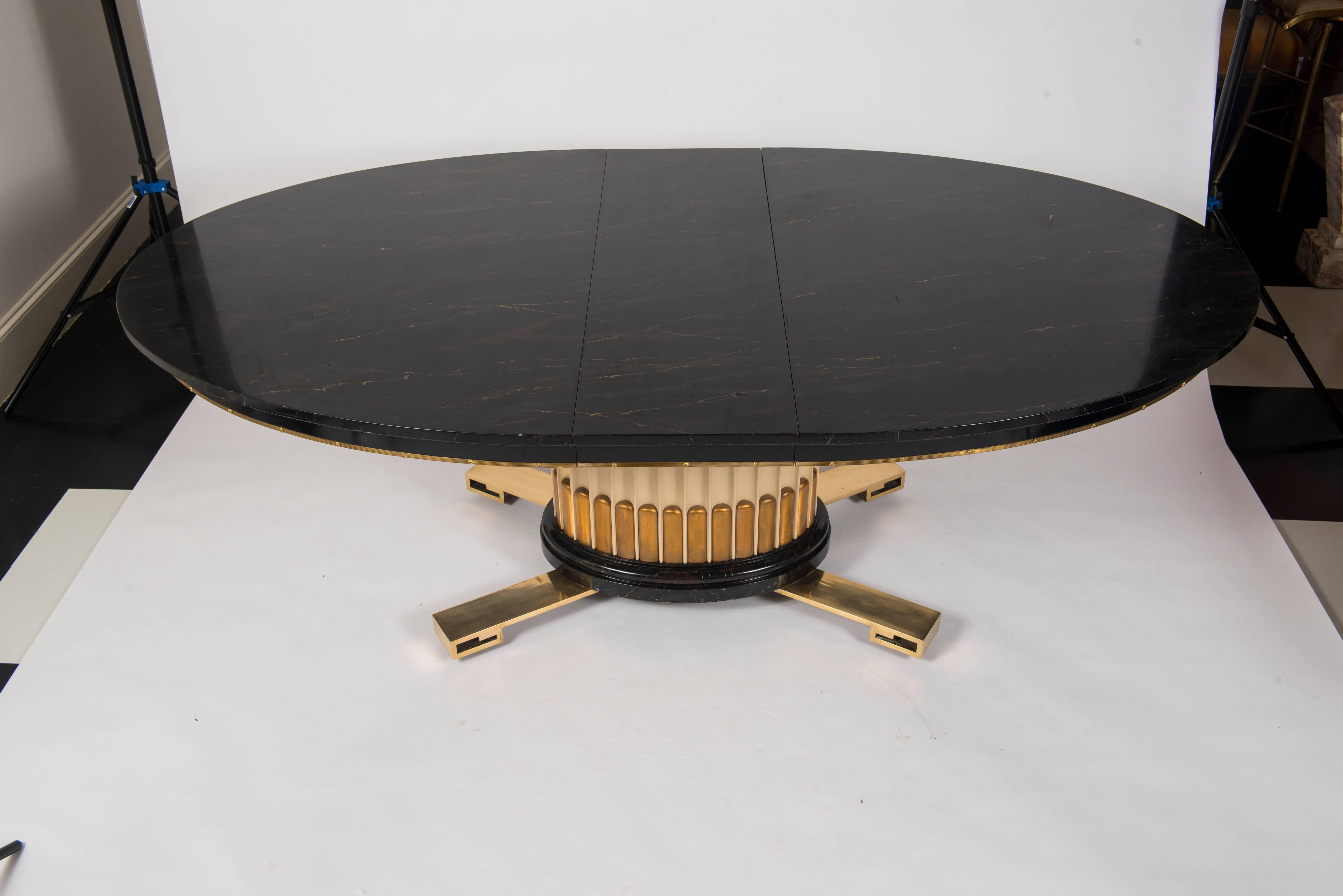 Exceptional extension dining table designed by Renzo Rutili for Johnson Furniture Company. Pedestal base resting on bronze Greek key feet with a faux marble finish oval top. Table is 71'' long excluding the two additional 14'' wide leaves. Beautiful