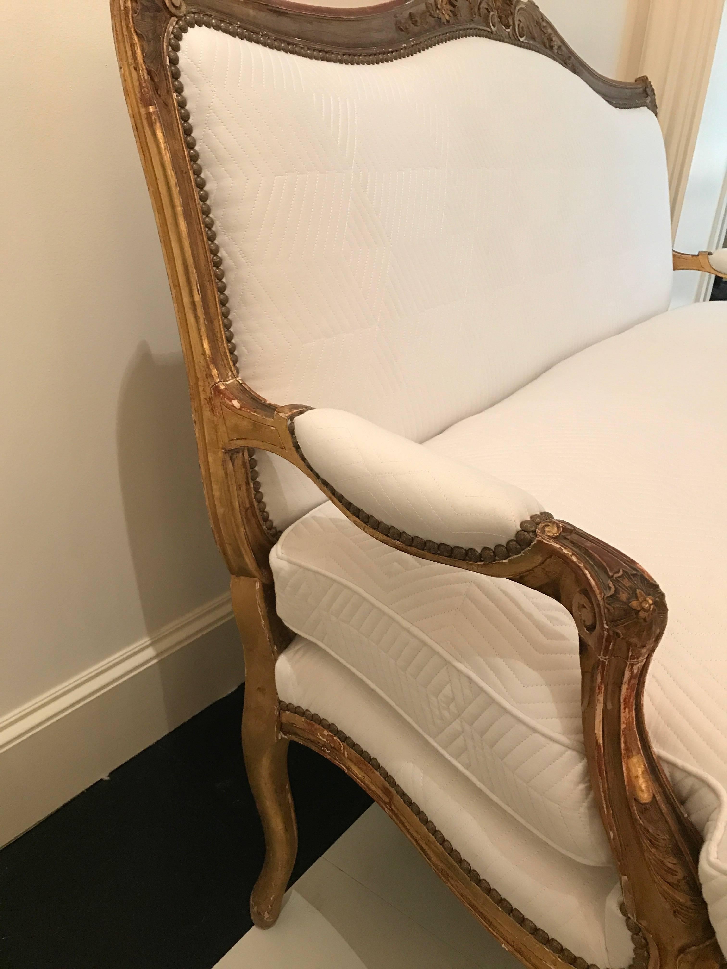 A chic 19th century Louis XV style giltwood sofa newly upholstered in a contemporary and modern white geometric quilted cotton fabric.