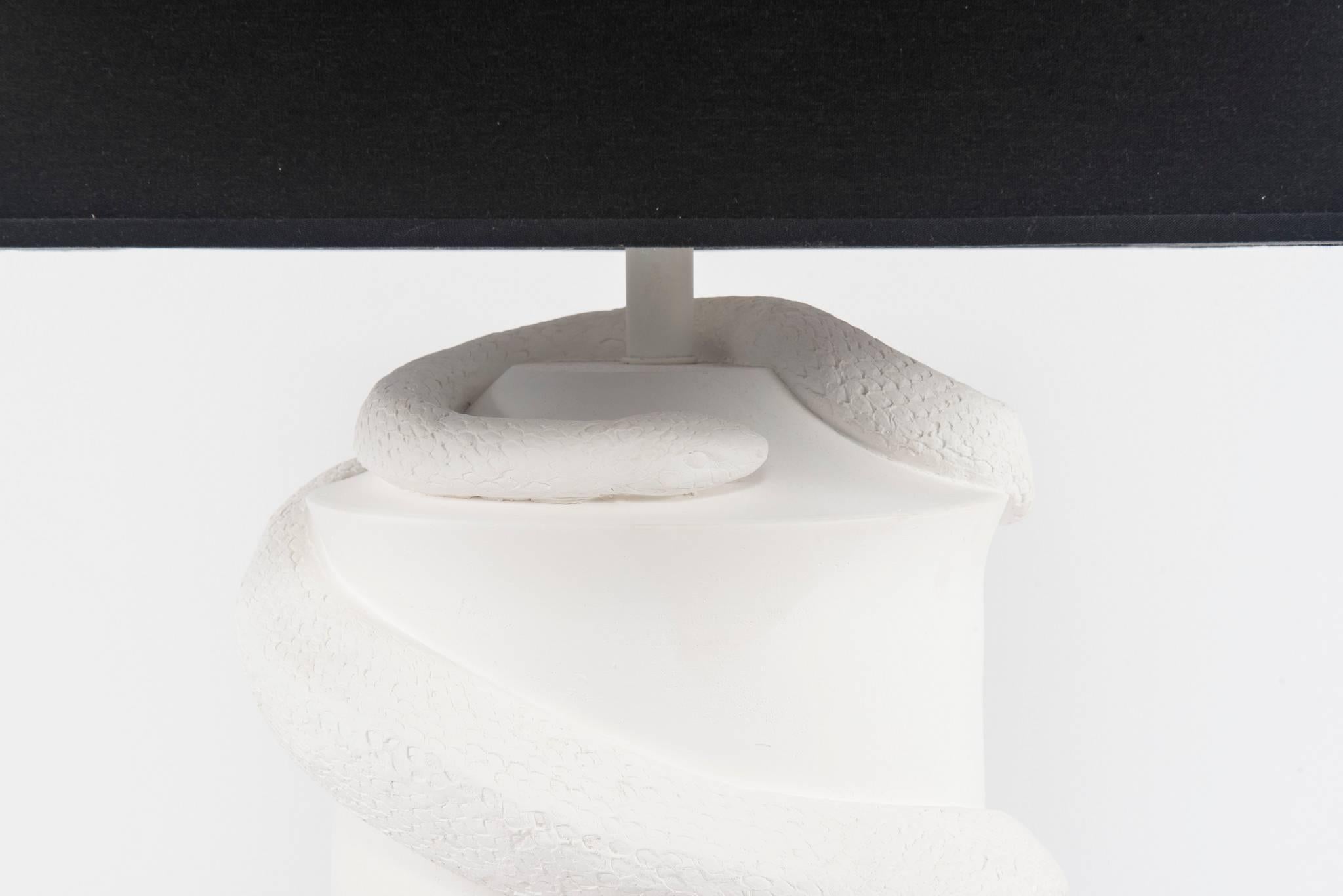 A monumental white bisque serpent lamp with black paper shade.

Shade is 18 inches x 18 inches
Lamp dimensions to the bottom of the socket 26.75 inches high.