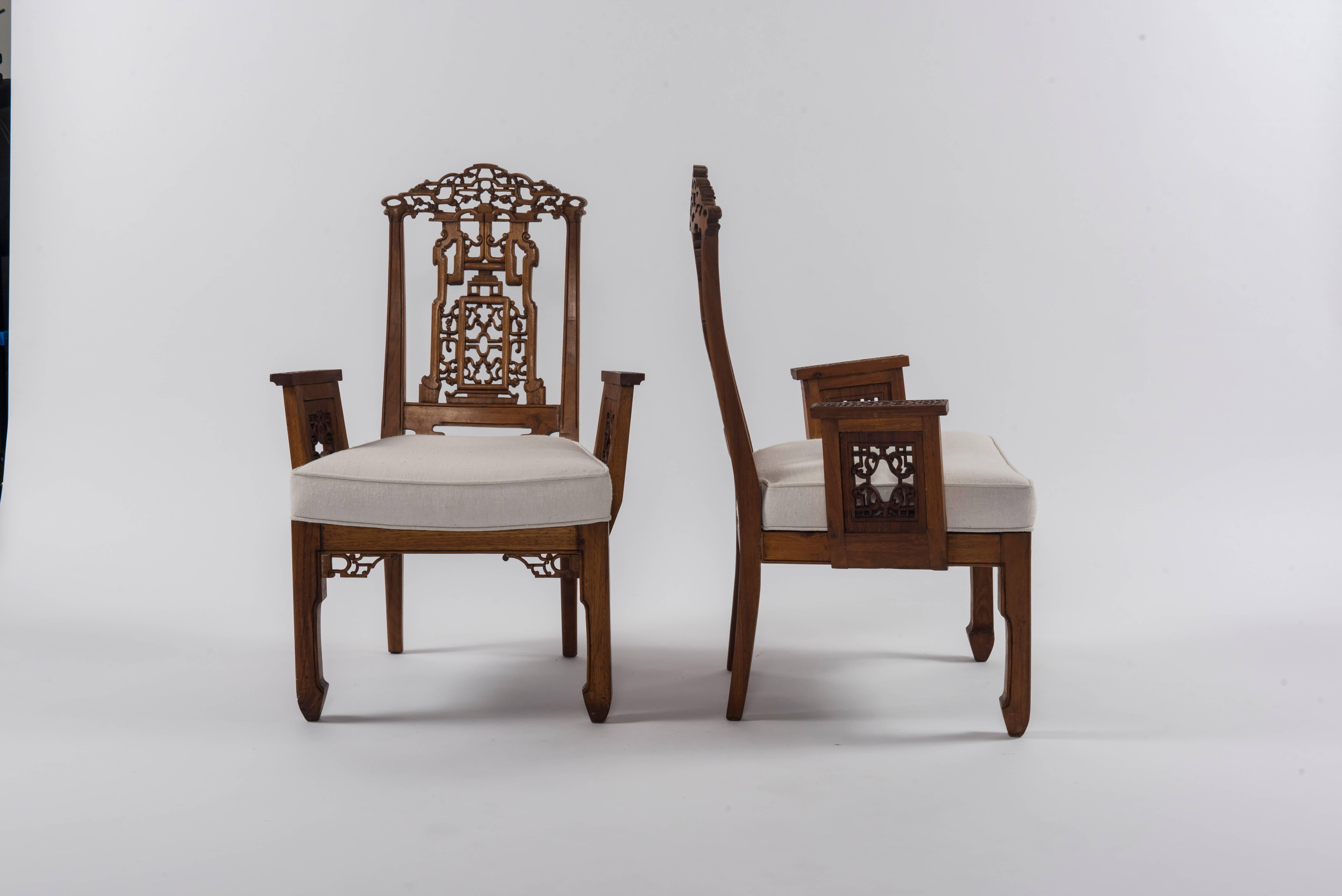 A 1940s pair of carved Chinese armchairs with newly upholstered and rebuilt seats in a white ecru natural linen.