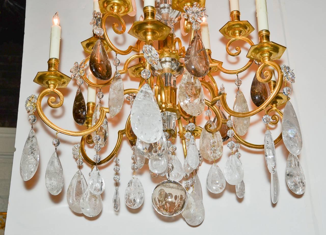 Exceptional 19th century French gilt bronze and heavy rock crystal twelve-light chandelier, circa 1880. Having gorgeous gilt bronze finish, elegant scrolling arms, large heavy rock crystal drop prisms and stunning central column.