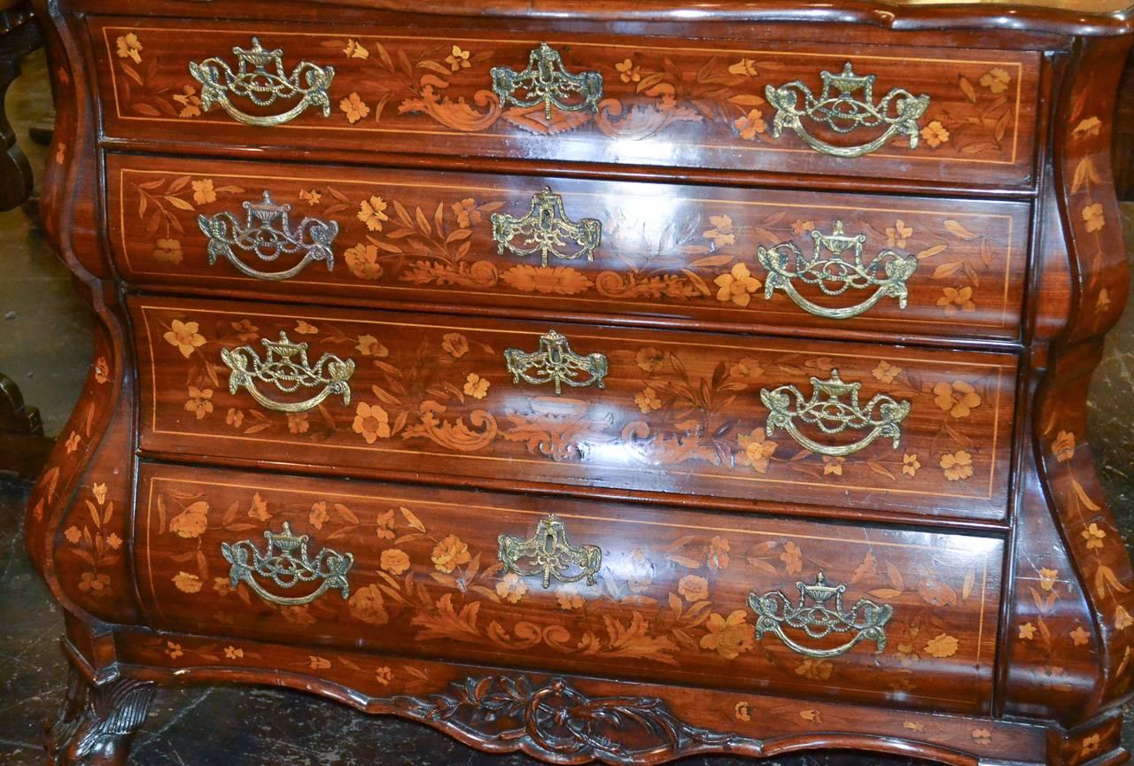 Marvelous 19th century Dutch marquetry inlaid four-drawer commode. Having shaped front, fabulous inlays in floral and acanthus leaf motif on all sides, elaborate antique brass hardware and resting on ball and claw feet. 