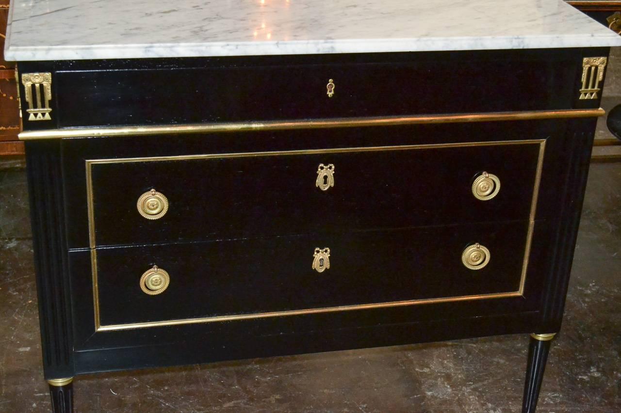 Sensational French Louis XVI black lacquered Jansen three-drawer commode. Having gilt bronze mounts and hardware, Carrara marble top and fluted tapered legs. Exhibiting clean lines.