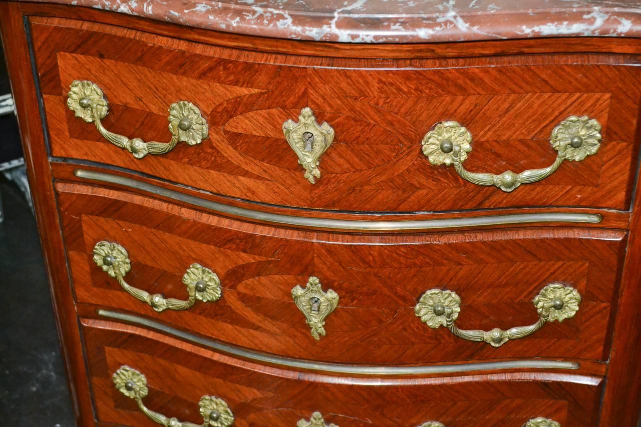 Wonderful 19th century French Regency kingwood four-drawer commode. Having Griotte rouge de belgique marble-top, stylish geometric motif across drawer fronts and sides and lovely gilt bronze hardware. 