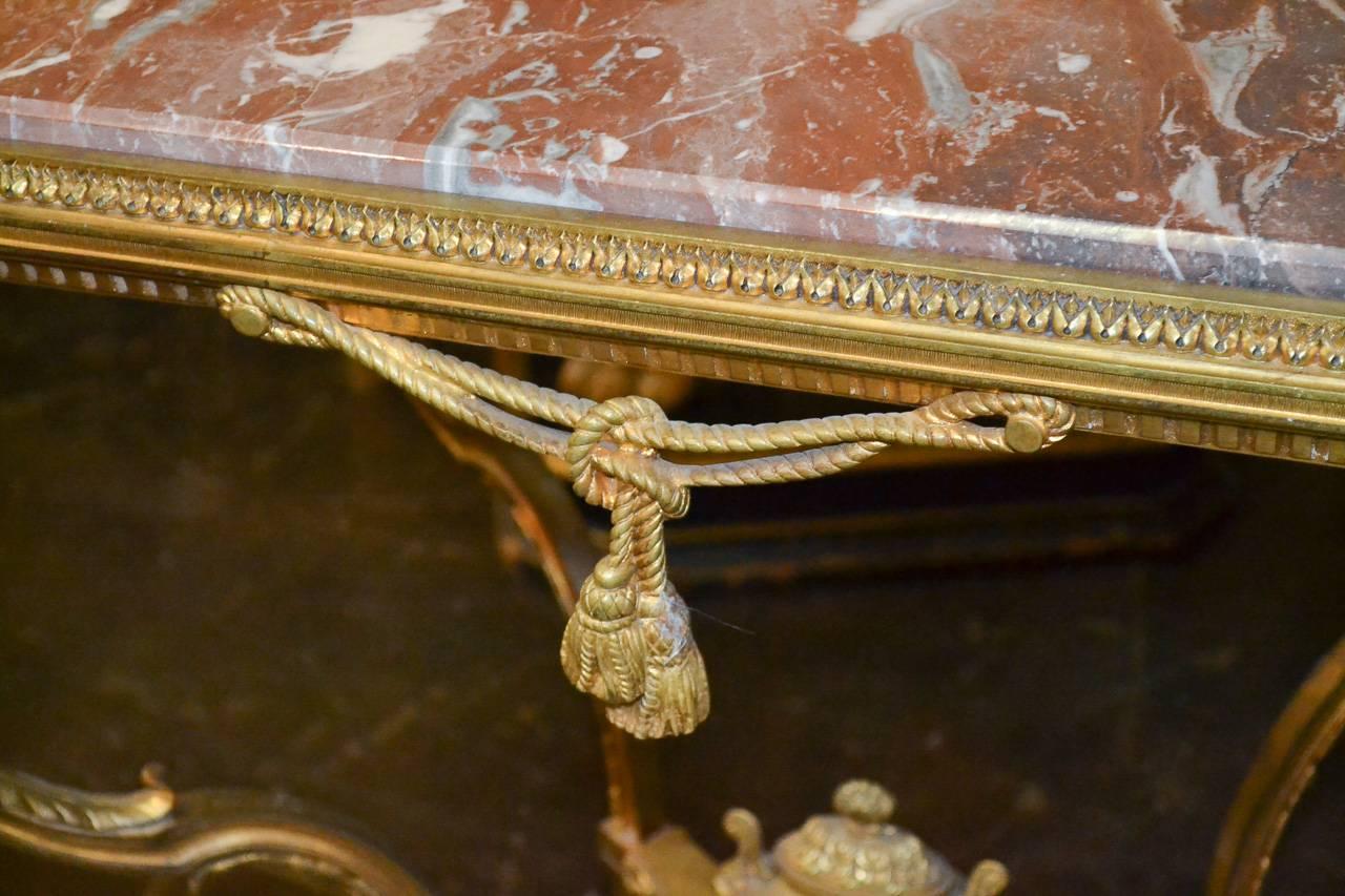 Exceptional 19th century French neoclassical gilt bronze occasional table with lovely Rouge Royal inset marble top. Having finely cast and detailed frame with figural mounts, capped urn stretcher and curved legs terminating in cloven feet. A very