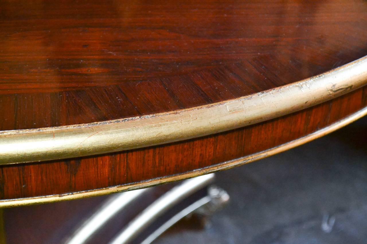 Marvelous 19th century English Regency rosewood and parcel-gilt center table. Having a wonderful warm and rich finish, stylishly accented with gold trim, and resting on gilt bronze claw feet with casters. A fantastic piece with clean lines that work