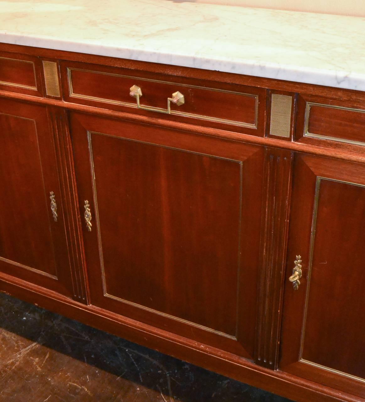 Sensational French, Jansen three-drawer over three-door mahogany server. Having bronze hardware and trim, beautiful Carrara marble top and resting on fluted tapered legs. Showcasing a lovely patina and clean lines that work in countless styles of