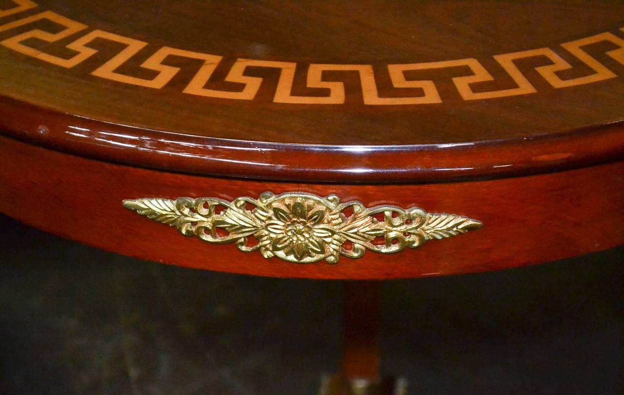 Elegant pair of Italian Empire side tables with ormolu mounts. Having detailed caryatid busts atop each leg, handsome Greek key inlaid tops, and each leg terminating in a claw foot resting on lovely base. 