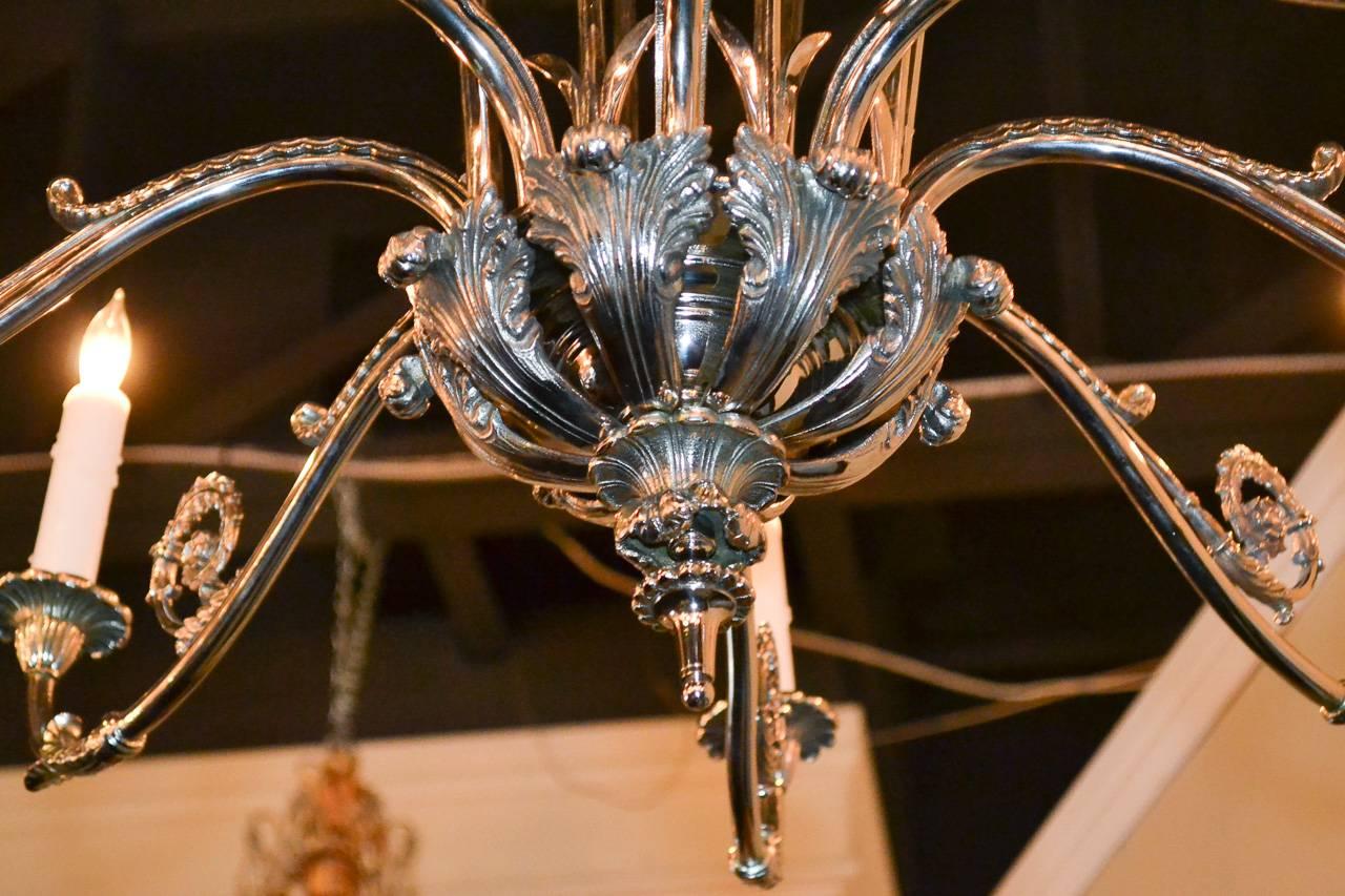 Sensational French directoire silver plated iron eight-light chandelier. Having graceful arms and bottom bowl adorned in acanthus leaf motif, central column comprised of arrows and exhibiting a beautiful silver finish. 