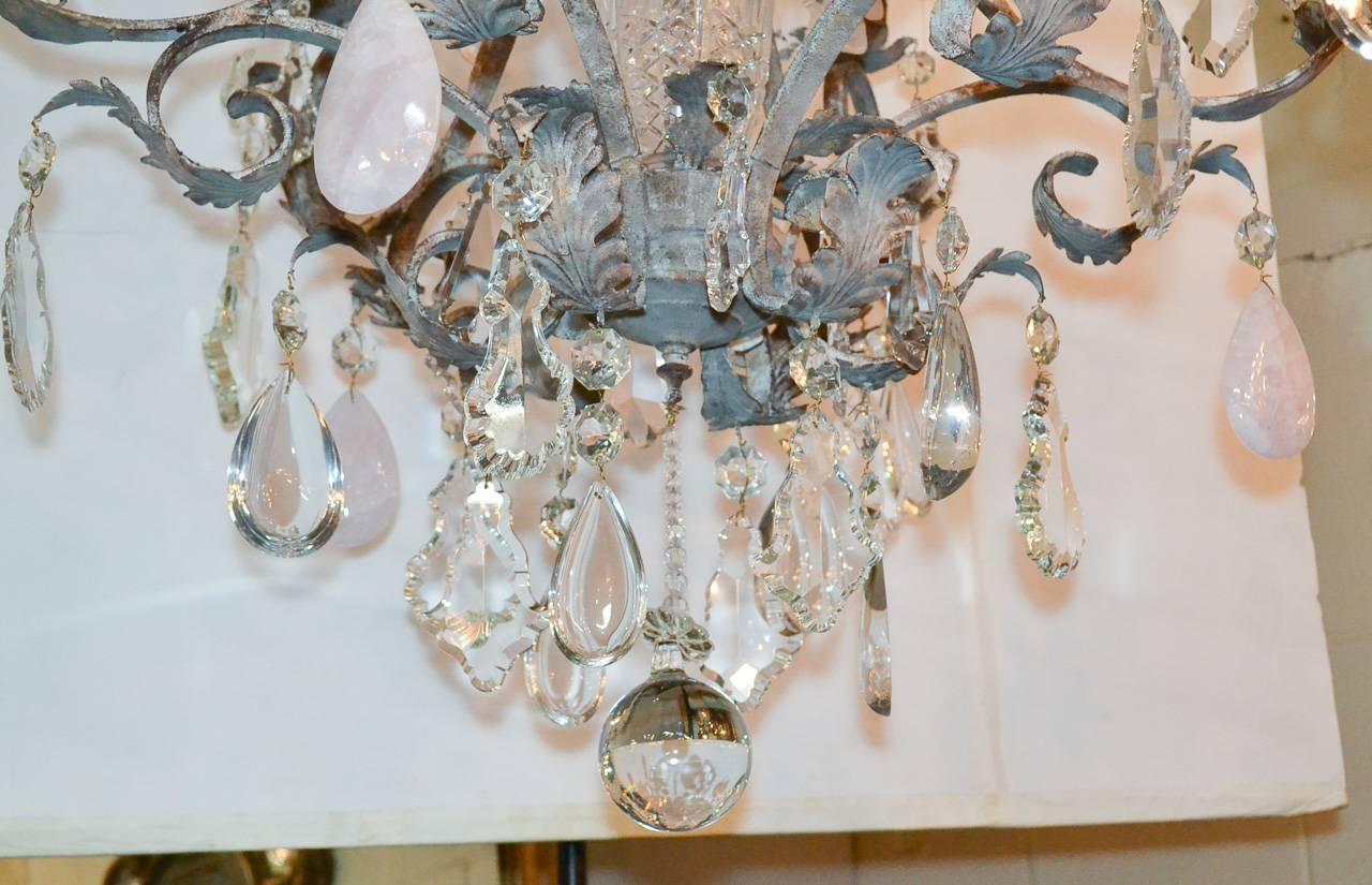 Gorgeous one of a kind Ernesto Klun textured iron twelve-light chandelier. Having both rock crystal and rose quartz prisms, lovely scrolling arms and bobeche in foliate motif, and large cut crystal center finial. 
 
