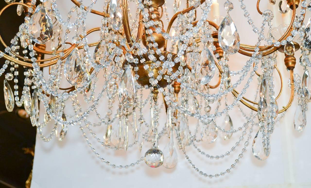Sensational Italian beaded crystal and giltwood twelve-light chandelier. Having lustrous gilt finish, graceful curved arms, and beautifully adorned with crystal beaded strands and drop prisms. 


 