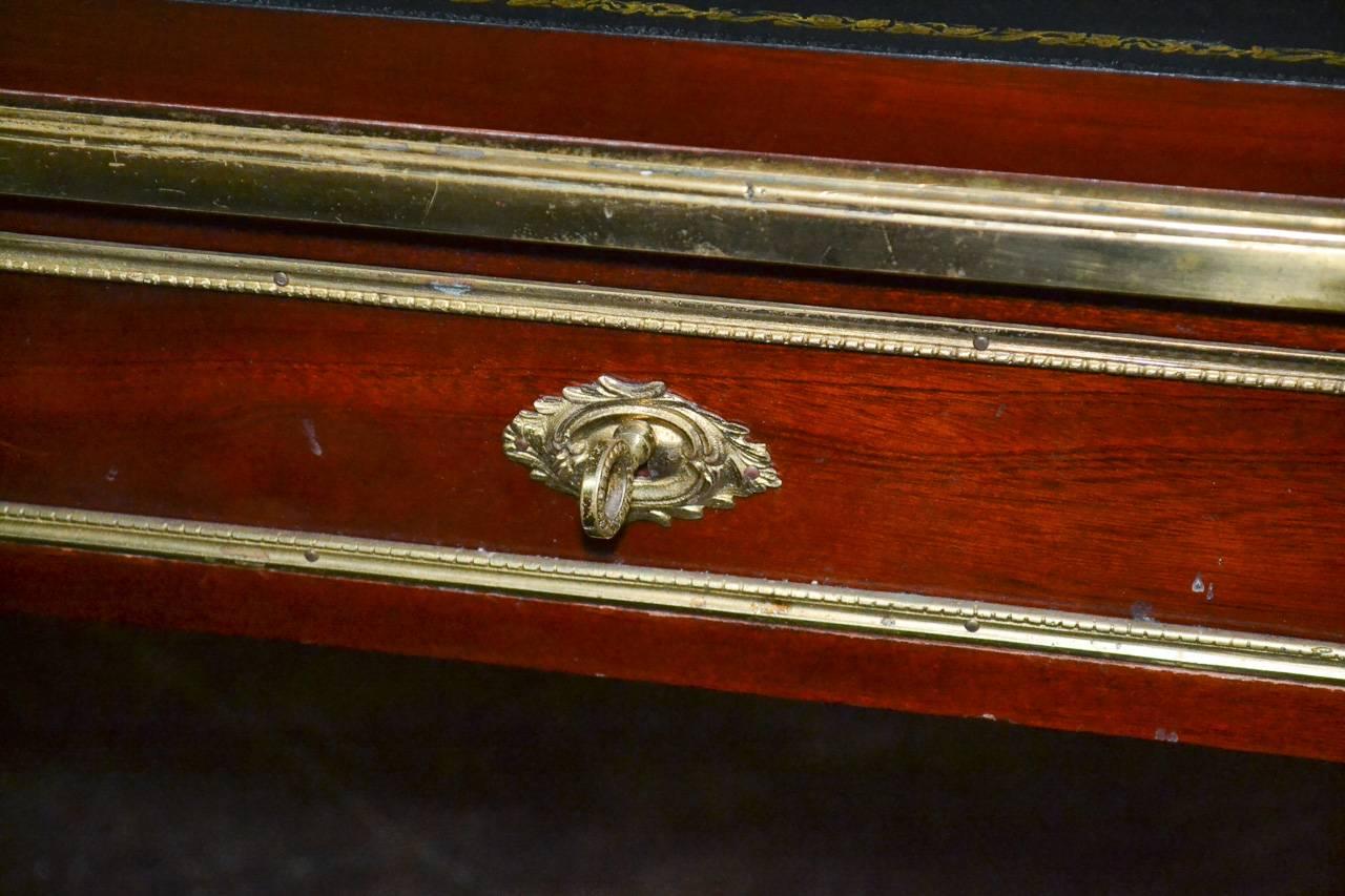 Marvelous fine French empire mahogany three-drawer writing desk. Having bronze hardware, gilt brass trim, tooled leather top and resting on tapered legs. Exhibiting a beautiful finish and patina, with clean lines suitable for many types of decor!