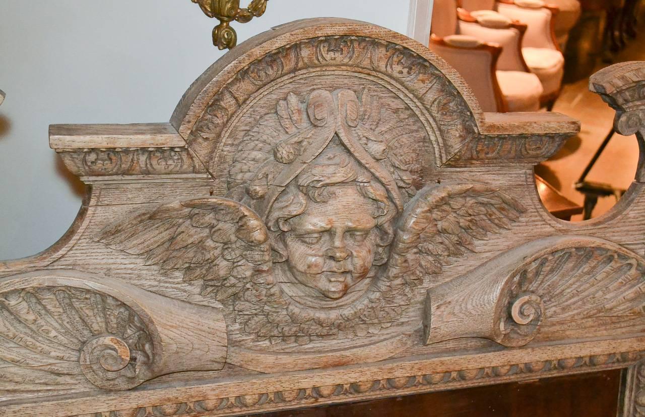 Splendid 19th century Italian hand-carved bleached oak mirror. Having superb carvings overall, pediment with mask of winged putti, and with foliate and scrolling motif accents. Exhibiting a lovely patina with Classic lines wonderful for numerous