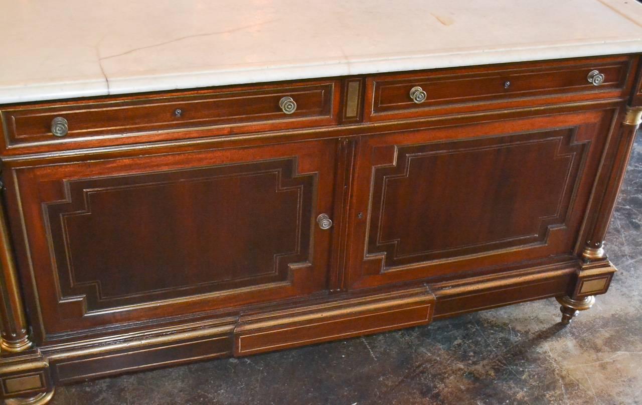 Wonderful 19th century French Directoire mahogany two-drawer over two-door buffet. Having lovely brass trim and inlays, Carrara marble top, handsome columnar supports, and resting on turned feet. 
 