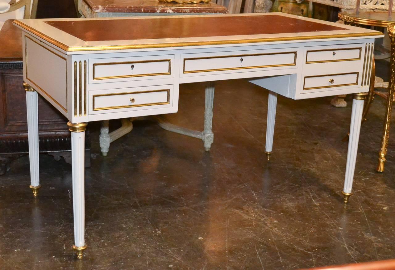 Marvelous French Jansen four-drawer lacquered writing desk. Having lovely brass trimmed detailing, tooled leather top, and resting on fluted tapered legs. Exhibiting a beautiful patina and clean lines that work in countless styles of decor!