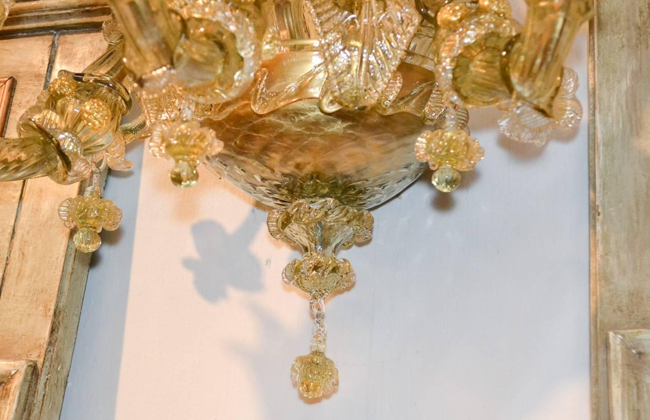 Exquisite pair of Venetian blown glass five-light sconces. Having detailed glass with gold accents, gracefully curved arms terminating in floral inspired candle cups, and lovely glass leaves and finial.
